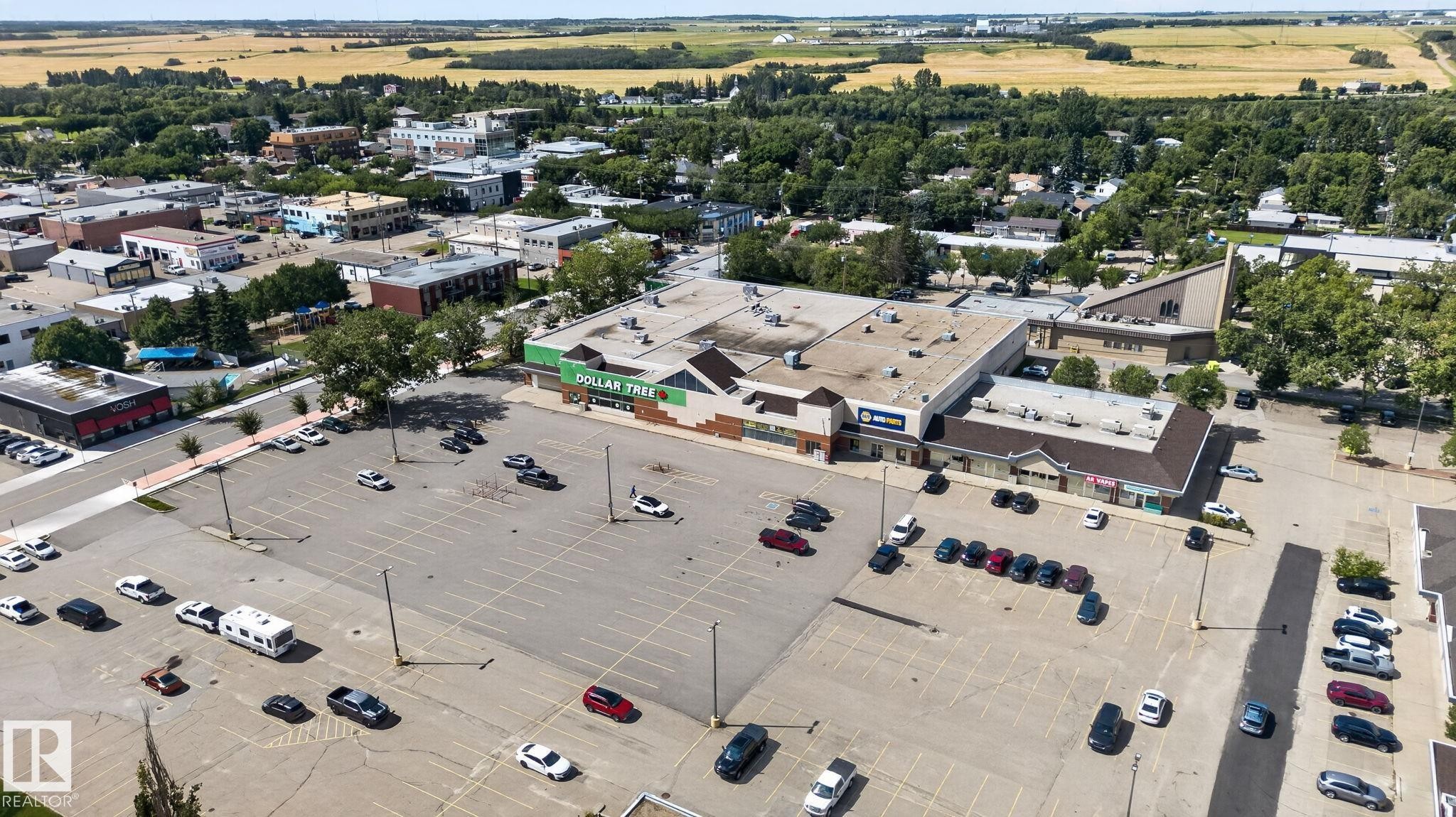 Expansive paved parking area for multiple vehicles, surrounded by commercial buildings and mature trees - 9921 109 Street, Fort Saskatchewan, AB - Outdoor With View