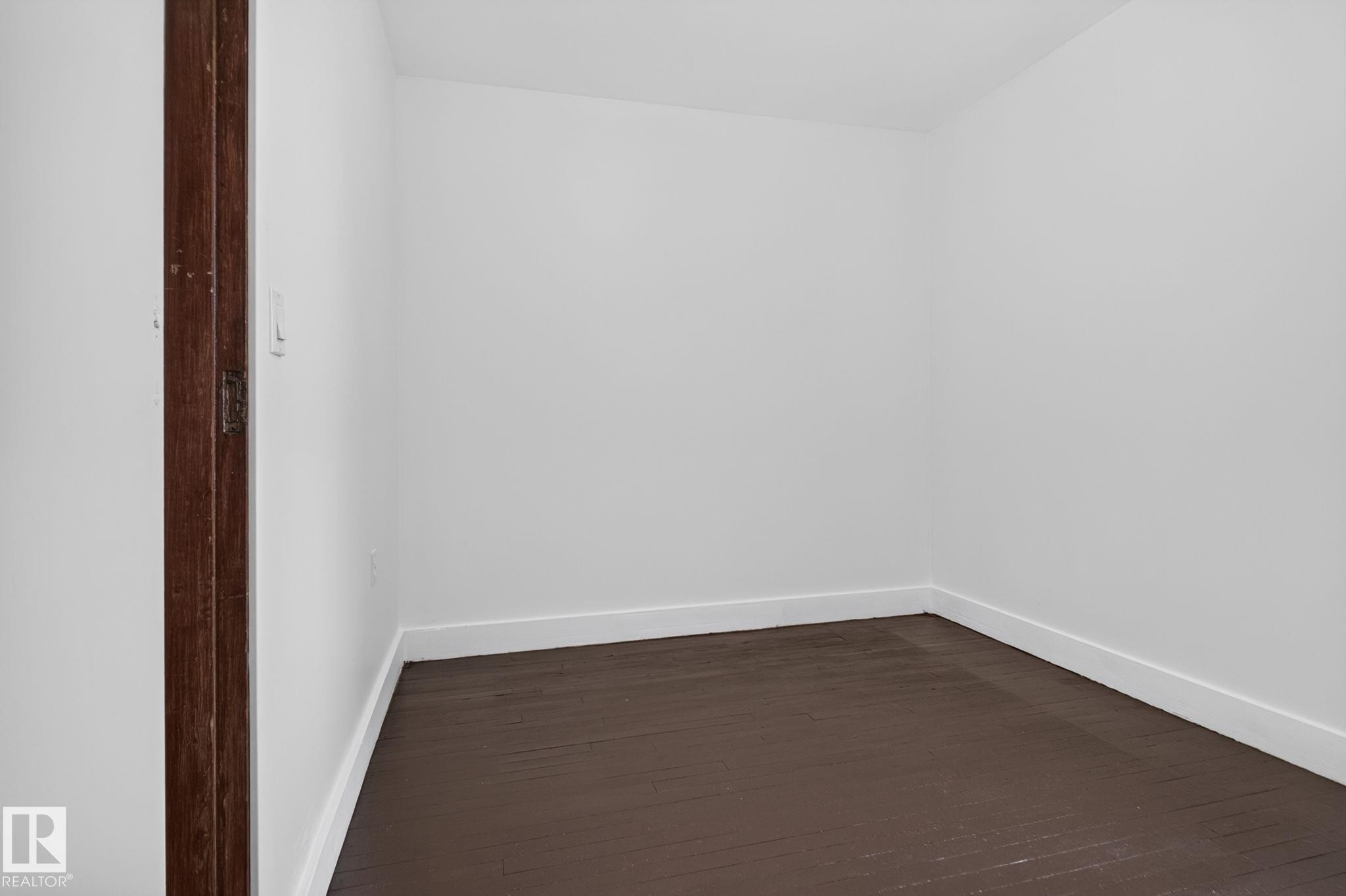 Crisp white walls with white trim, dark wood-finish flooring, and a dark wood door frame - 9921 109 Street, Fort Saskatchewan, AB - Indoor Photo Showing Other Room