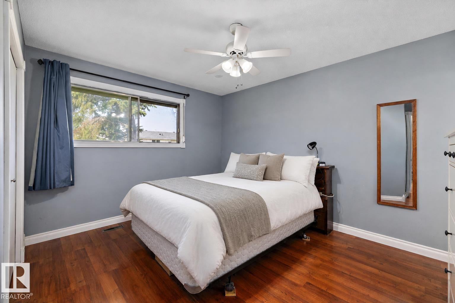 Wood-finish flooring, ceiling fan with integrated lighting, and a window offering natural illumination - 3511 73 Street Nw, Edmonton, AB - Indoor Photo Showing Bedroom
