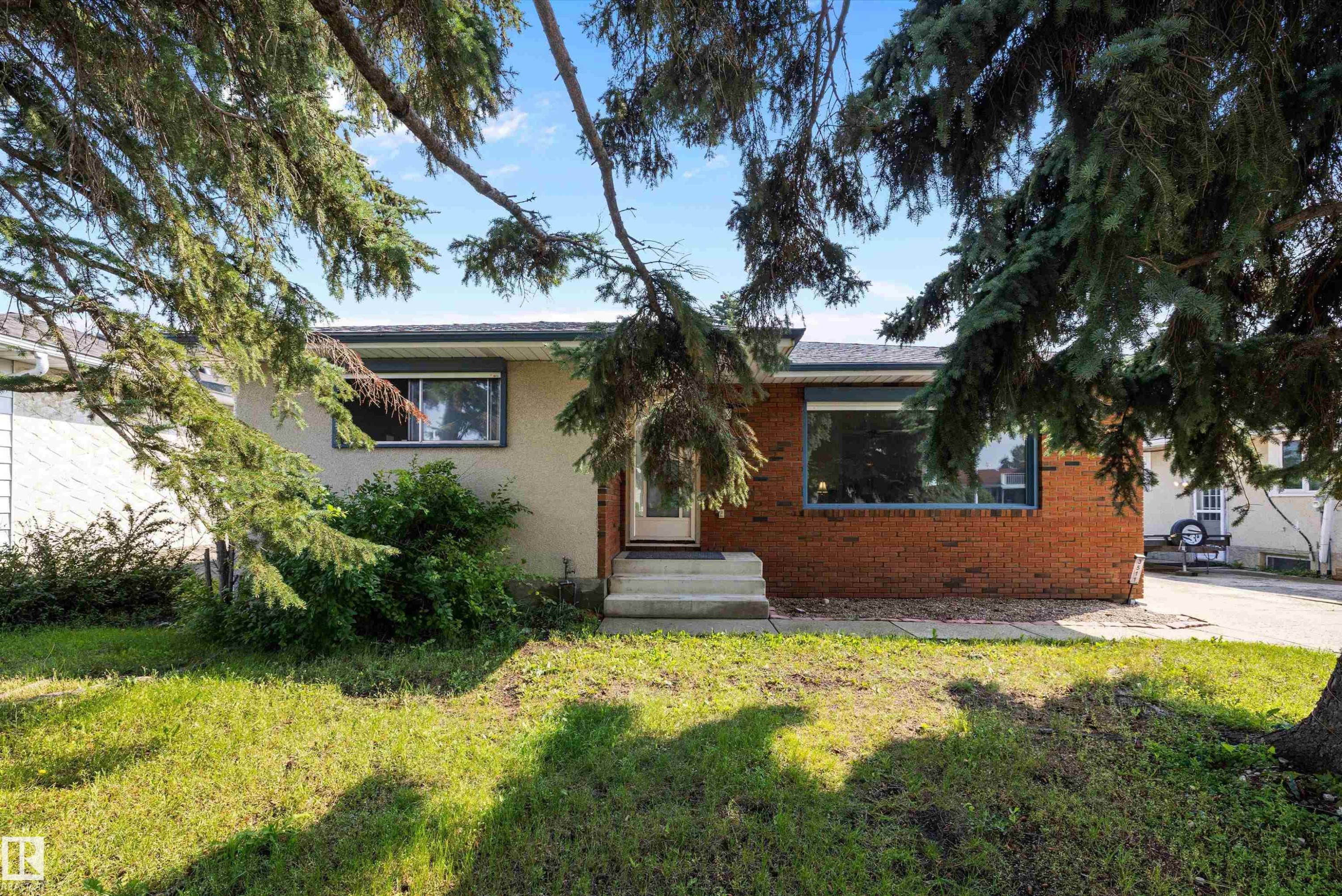 Charming brick and stucco residence featuring a mature tree-lined front yard with established landscaping - 3511 73 Street Nw, Edmonton, AB - Outdoor