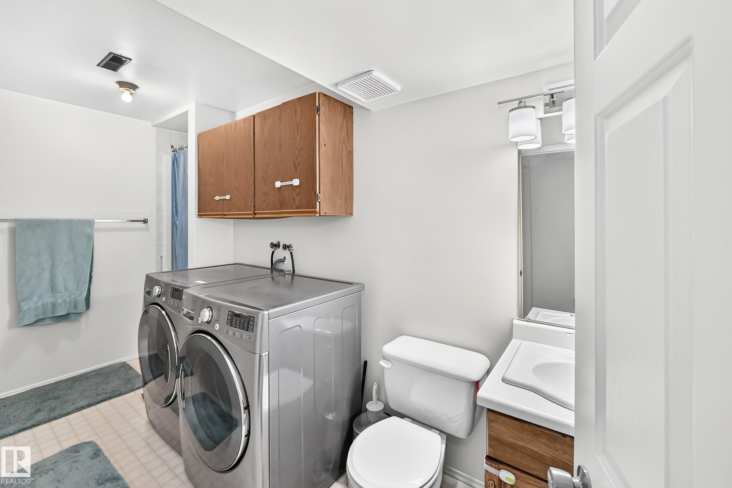 Hard-surface flooring, wood-finish cabinetry, and a vanity with a rectangular sink - 2404 37 Street Nw, Edmonton, AB - Indoor Photo Showing Laundry Room