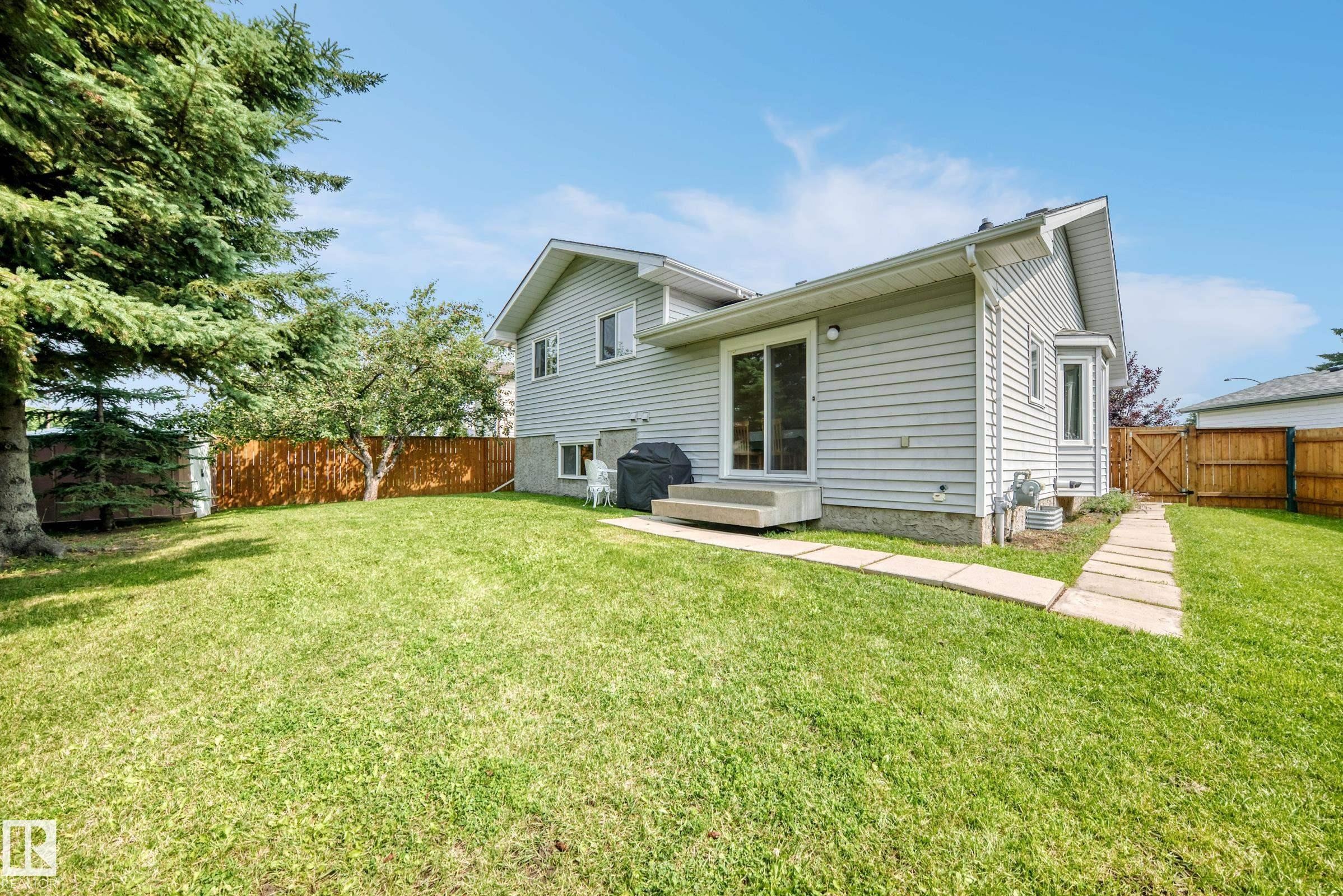 Spacious backyard with a vibrant lawn, wood privacy fence, and concrete paver pathway - 2404 37 Street Nw, Edmonton, AB - Outdoor