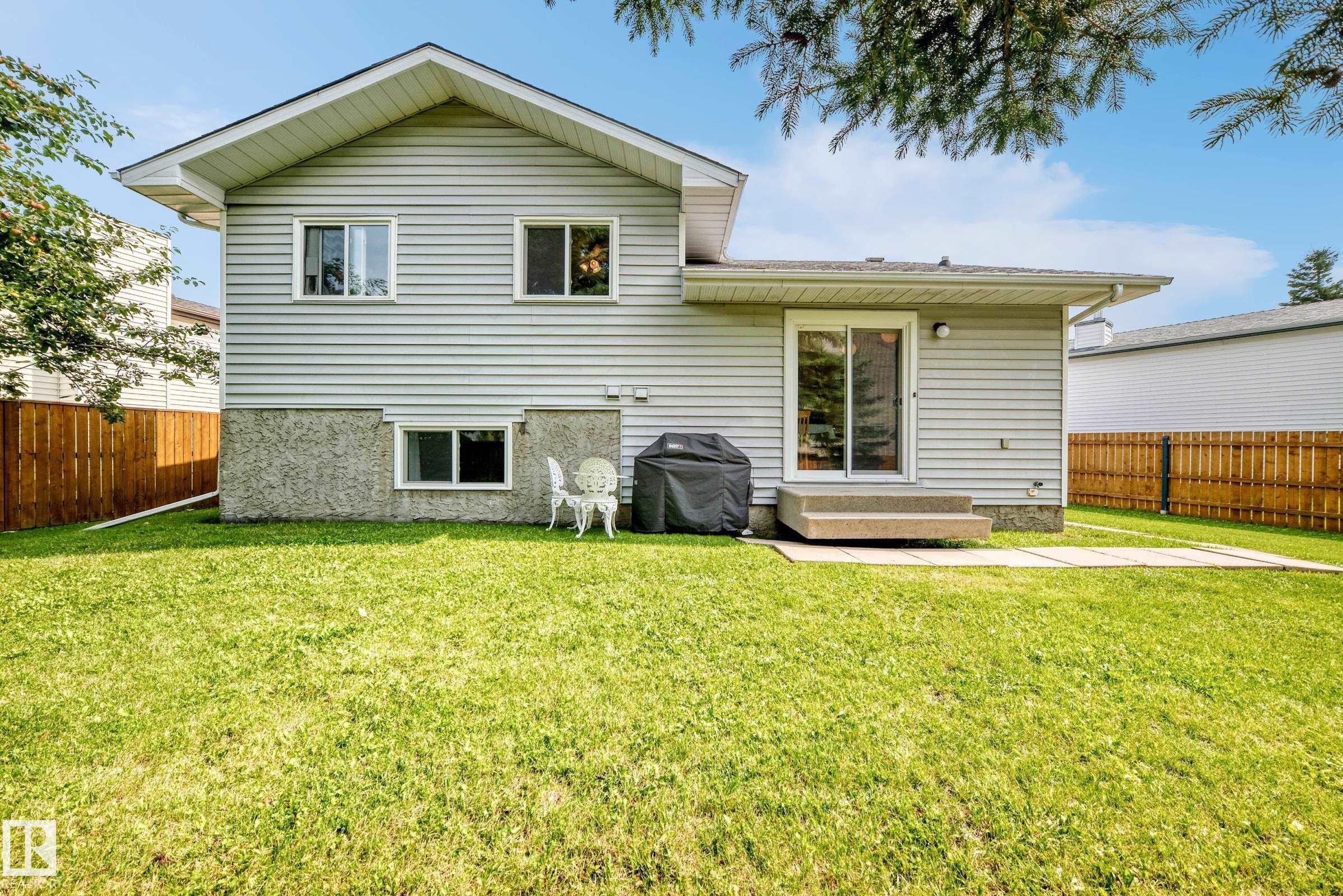 Spacious backyard featuring a lush lawn, privacy fencing, and a concrete patio - 2404 37 Street Nw, Edmonton, AB - Outdoor