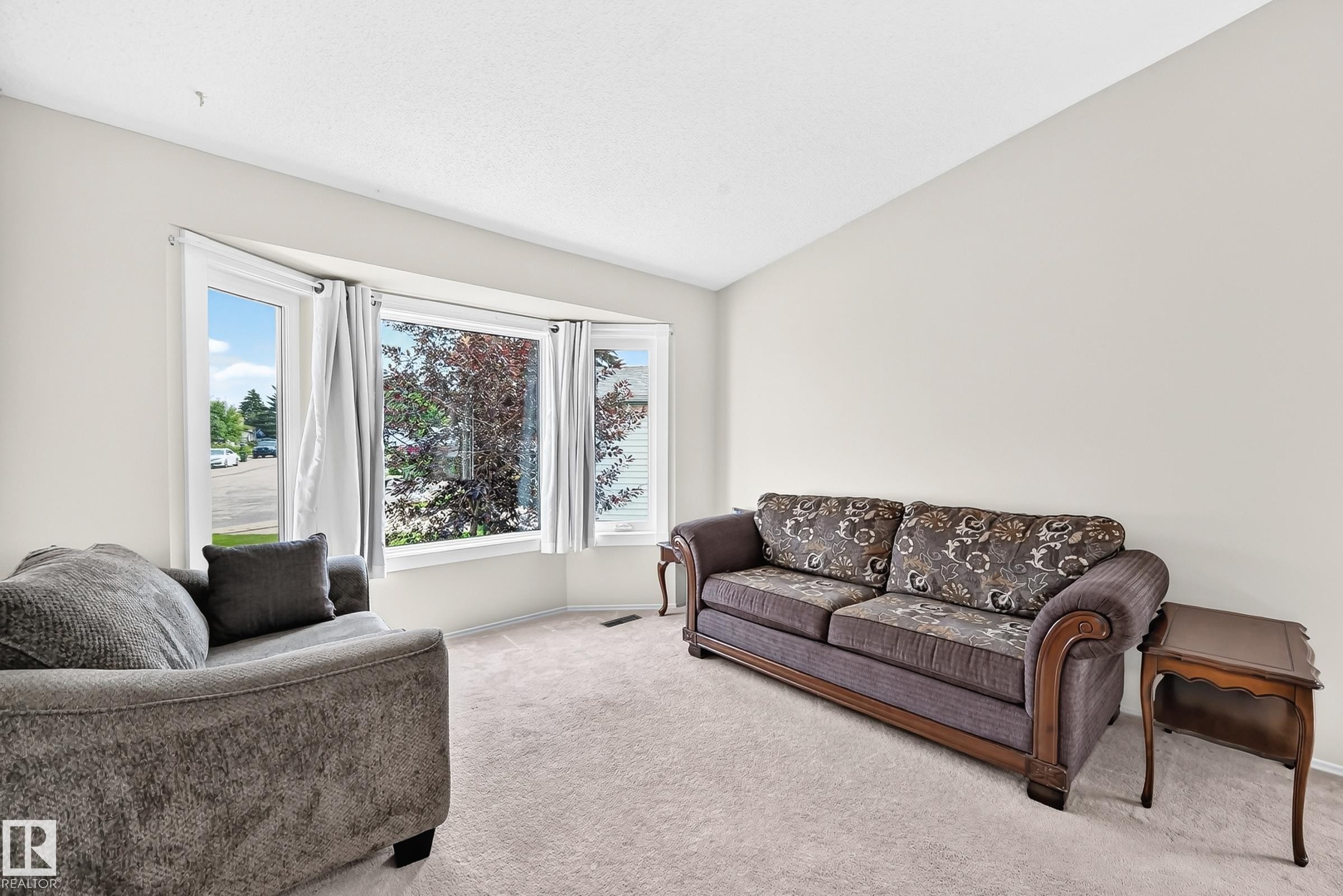 Bay window with multiple panels, soft carpet flooring, and light-toned wall finishes - 2404 37 Street Nw, Edmonton, AB - Indoor Photo Showing Living Room