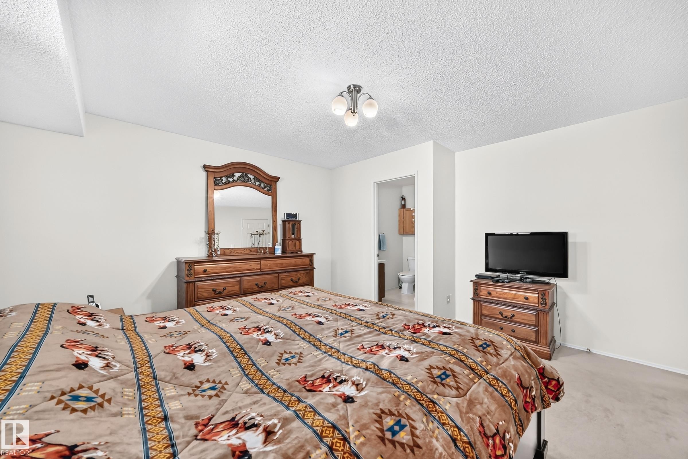 Carpeted flooring, neutral wall tones, and an attached three-light ceiling fixture - 2404 37 Street Nw, Edmonton, AB - Indoor Photo Showing Bedroom