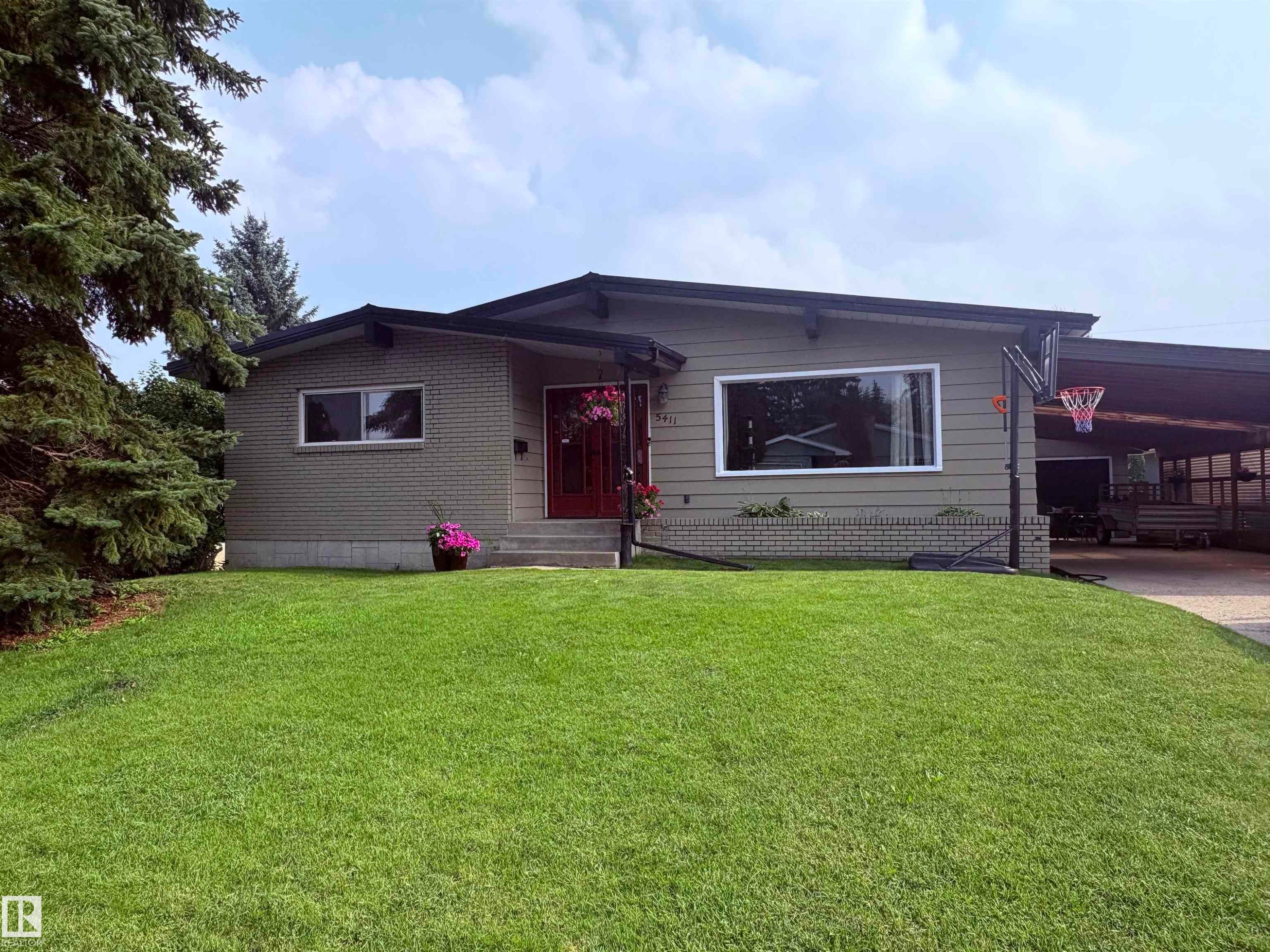 Mid-century modern residence featuring a brick and siding exterior, expansive front window, covered carport, and a well-maintained front lawn - 5411 44 Ave, Wetaskiwin, AB - Outdoor