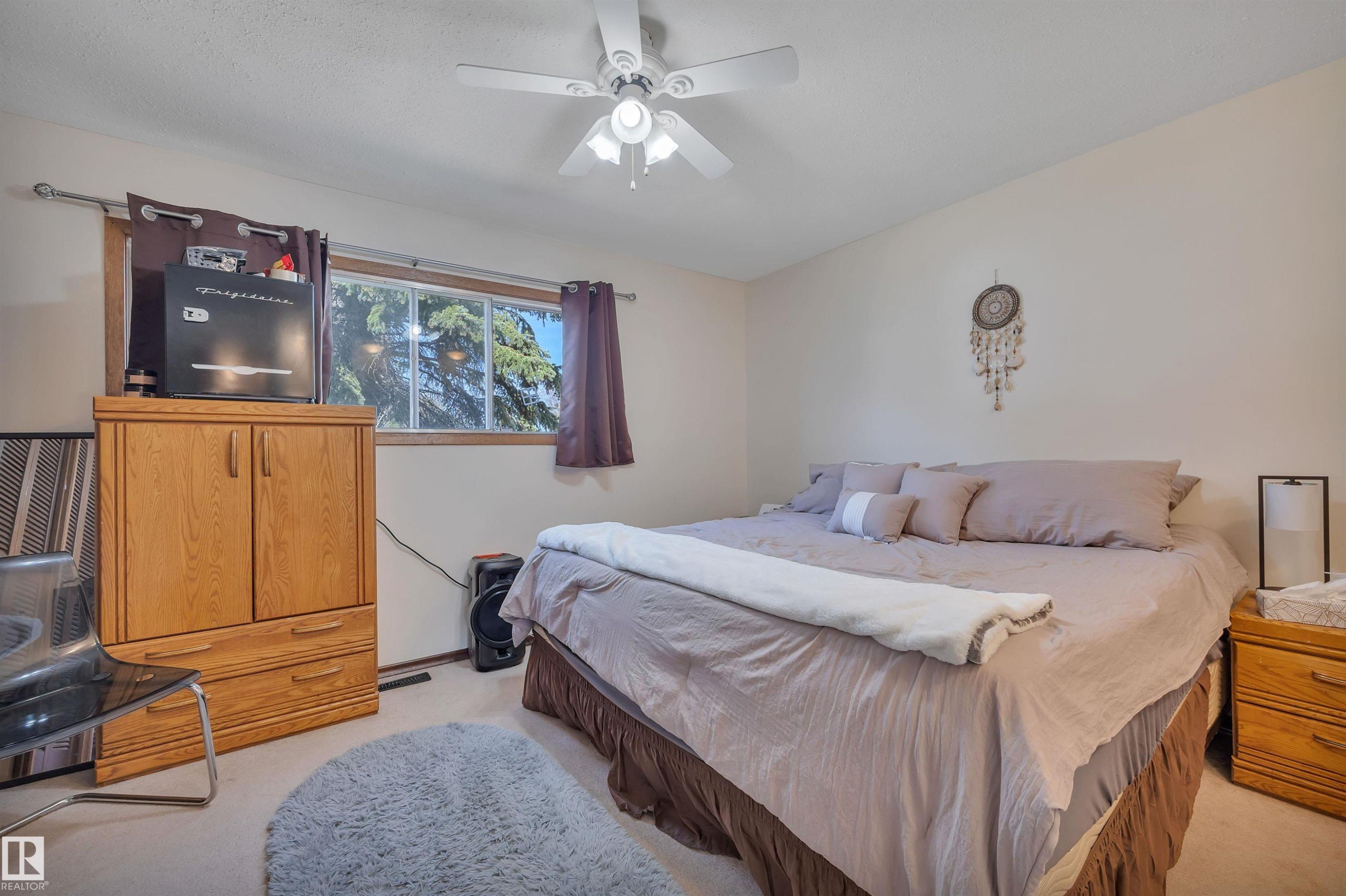 Bedroom featuring carpet flooring, a ceiling fan with integrated lighting, and a window with wood trim - 5411 44 Ave, Wetaskiwin, AB - Indoor Photo Showing Bedroom