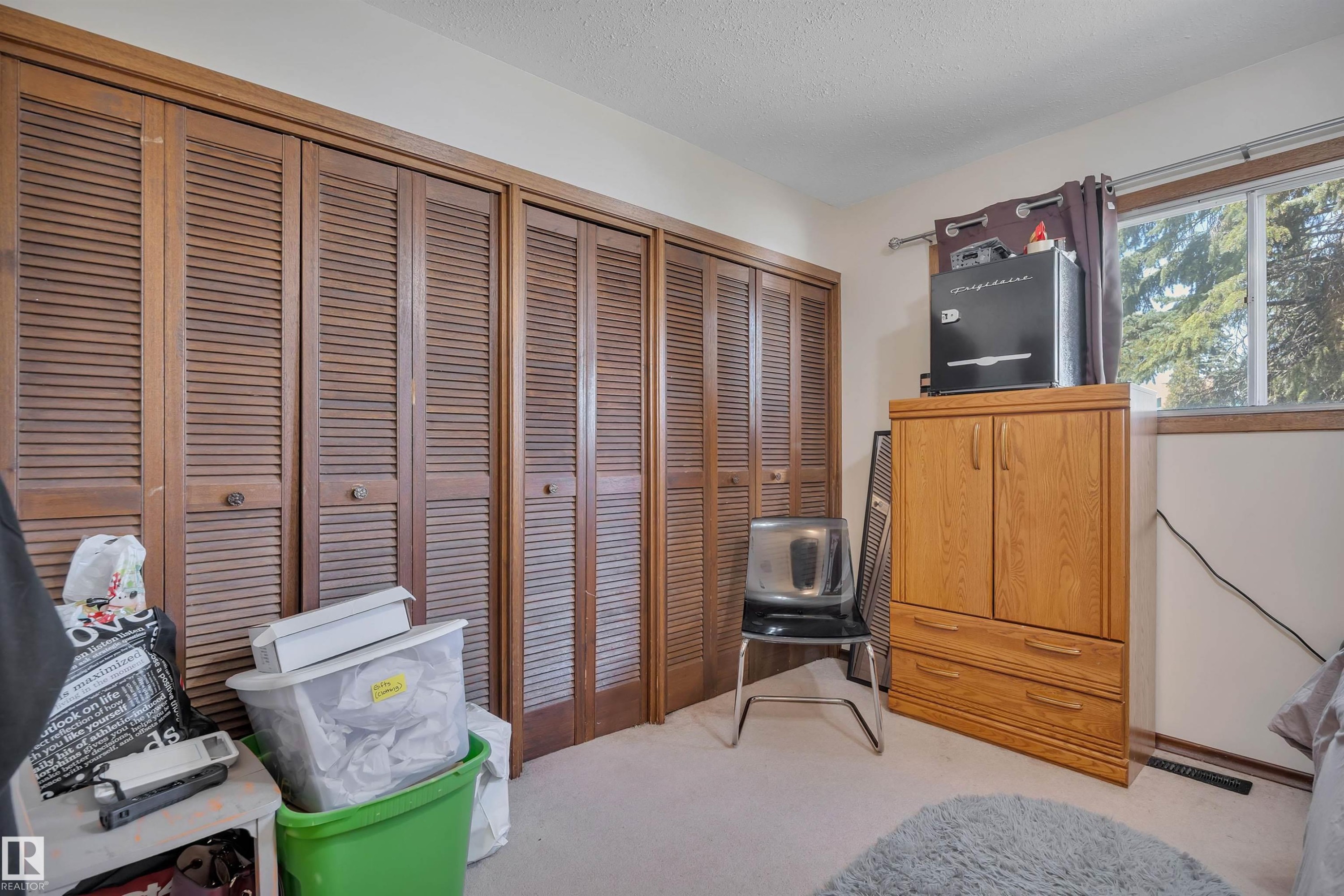 Wood-finish louvered closet doors spanning the wall, offering significant storage potential - 5411 44 Ave, Wetaskiwin, AB - Indoor