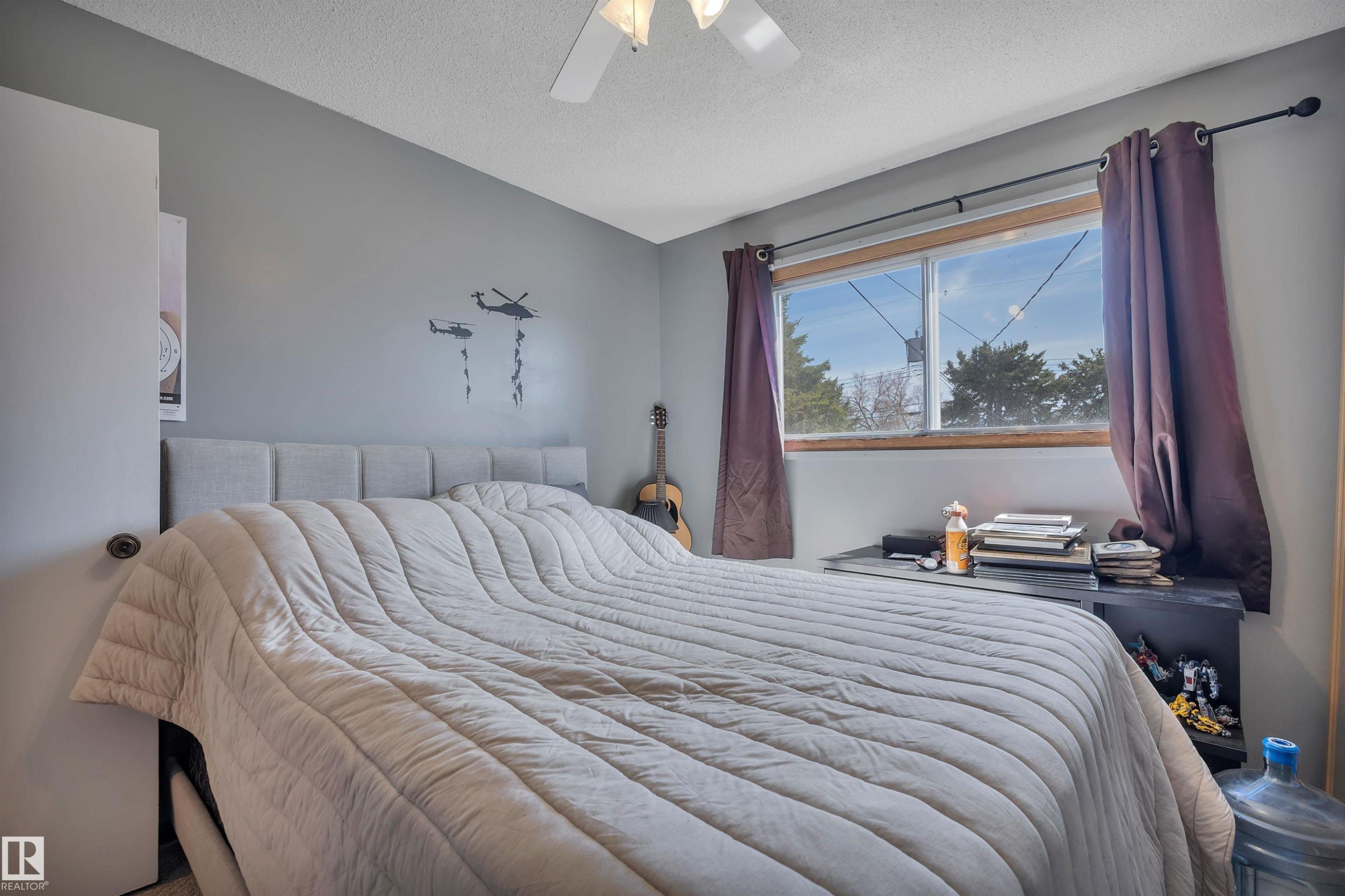 Bedroom featuring a window with wood trim, ceiling fan, and grey wall color - 5411 44 Ave, Wetaskiwin, AB - Indoor Photo Showing Bedroom