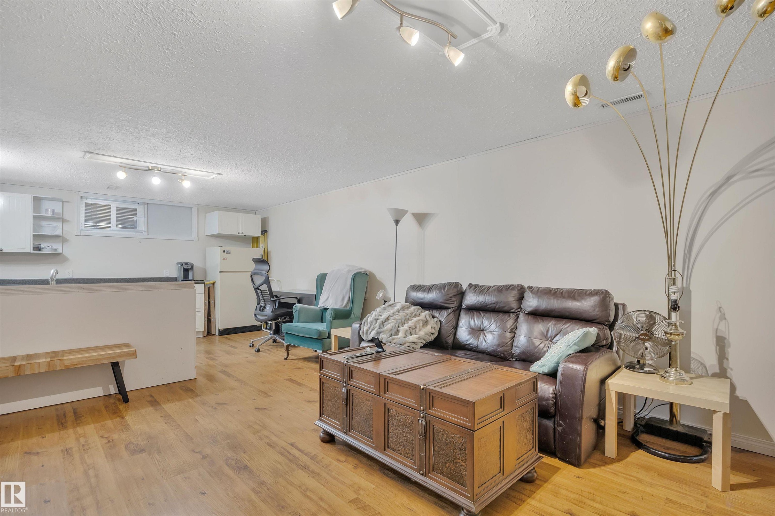 Open-concept living area featuring wood-finish flooring, white walls, and track lighting - 5411 44 Ave, Wetaskiwin, AB - Indoor