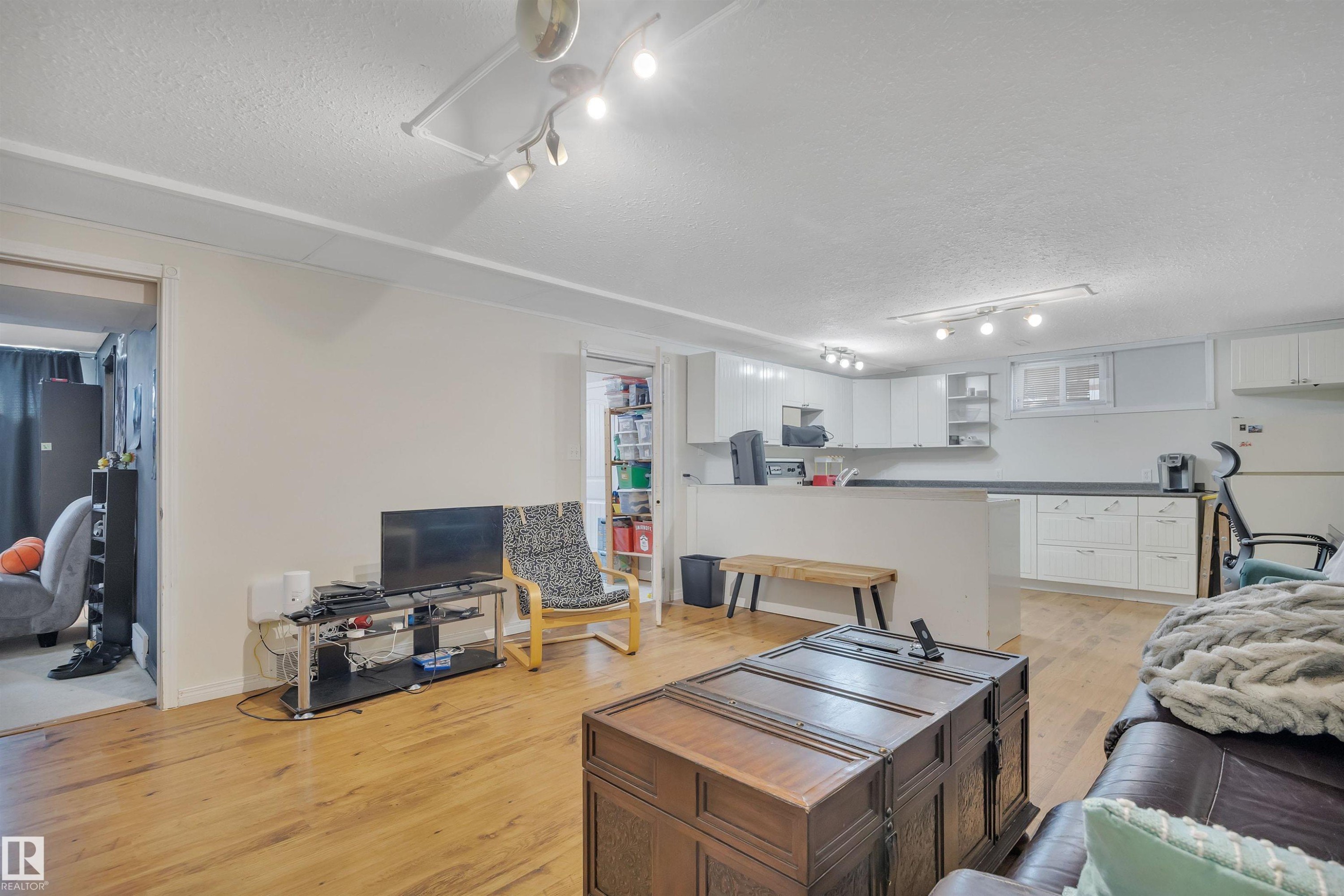Open concept living area featuring wood-finish flooring, recessed lighting, and a kitchen with white cabinetry and dark countertops - 5411 44 Ave, Wetaskiwin, AB - Indoor
