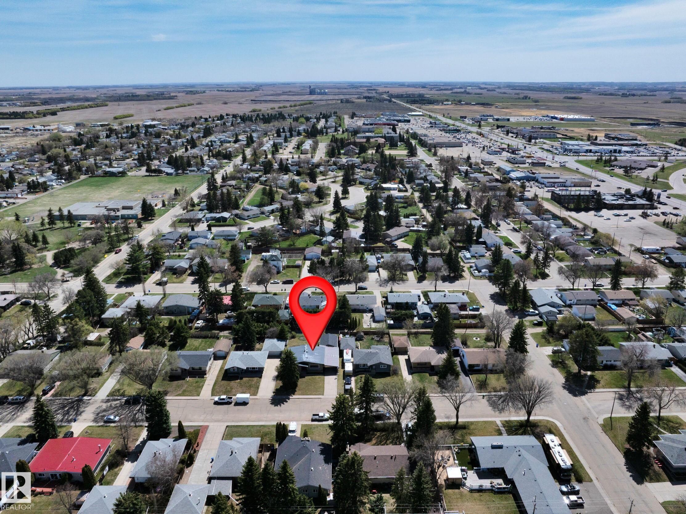 Aerial perspective showcasing a residential neighborhood with established trees, paved streets, and a commercial area in the distance - 5411 44 Ave, Wetaskiwin, AB - Outdoor With View