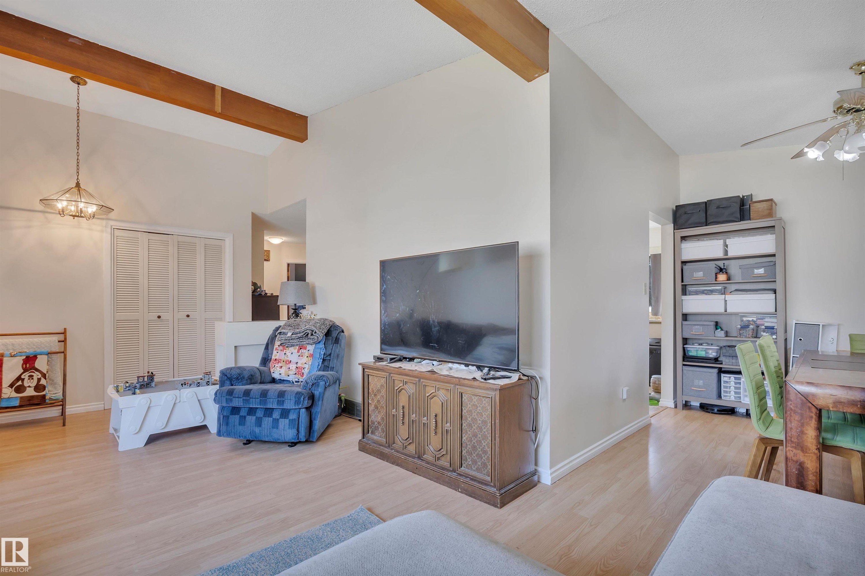Vaulted ceiling with exposed wood beams, light wood-finish flooring, and a built-in closet with bifold doors - 5411 44 Ave, Wetaskiwin, AB - Indoor