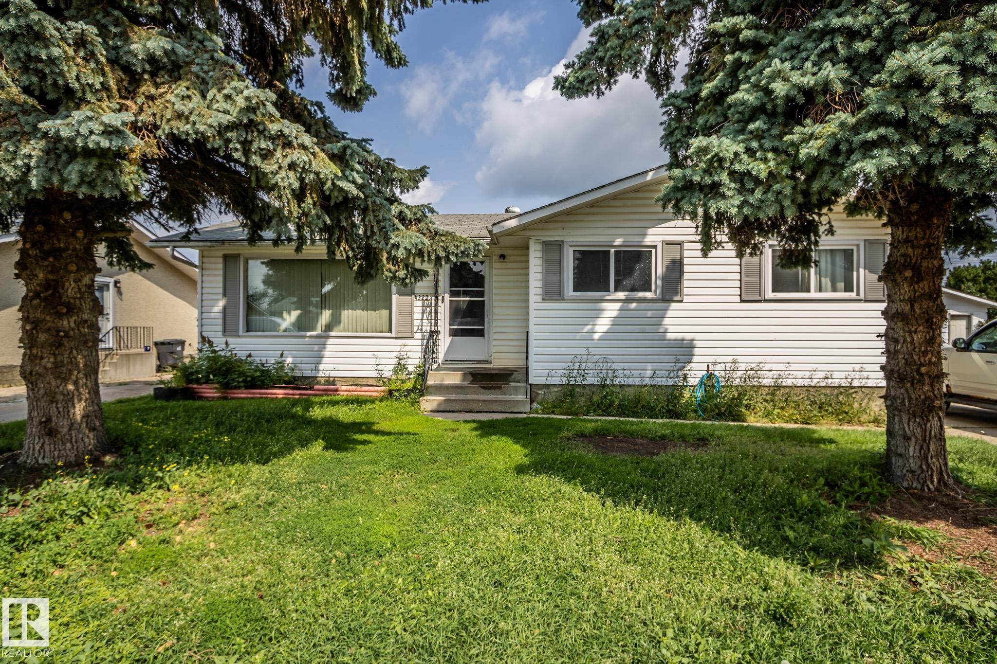 White siding exterior with grey window shutters, mature front yard trees, and a concrete front entry - 4322 49 Ave, St. Paul Town, AB - Outdoor