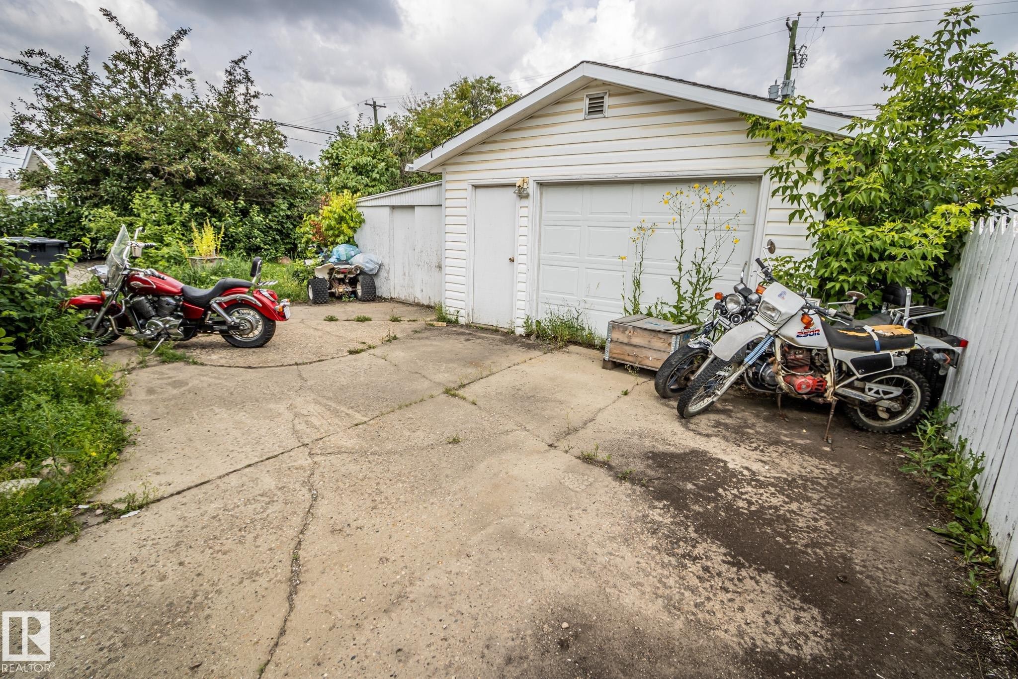 Detached garage featuring white siding, a single garage door, and a concrete driveway - 4322 49 Ave, St. Paul Town, AB - Outdoor