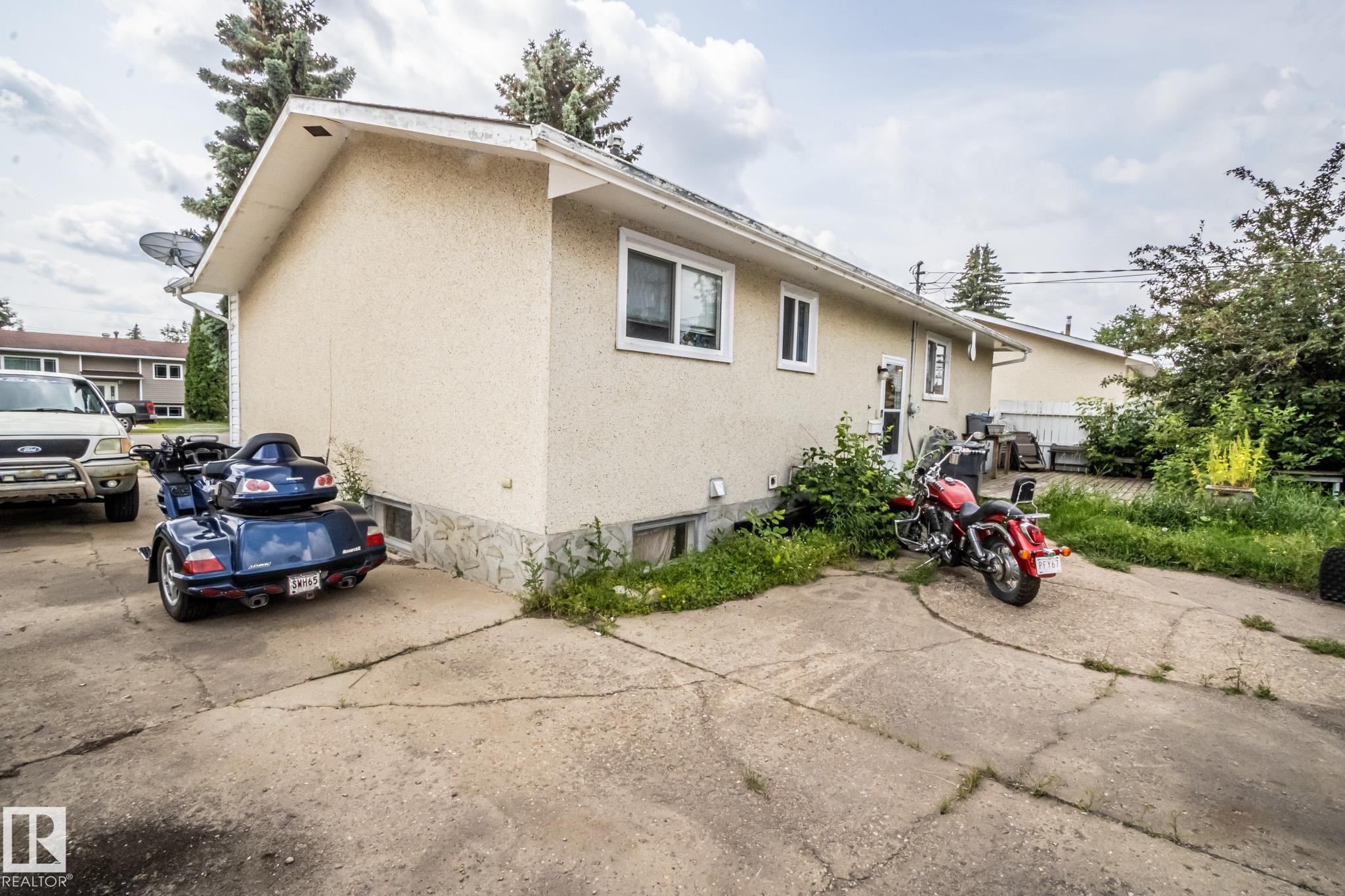 Exterior building with stucco finish, stone veneer foundation, white-framed windows, and concrete driveway - 4322 49 Ave, St. Paul Town, AB - Outdoor With Exterior