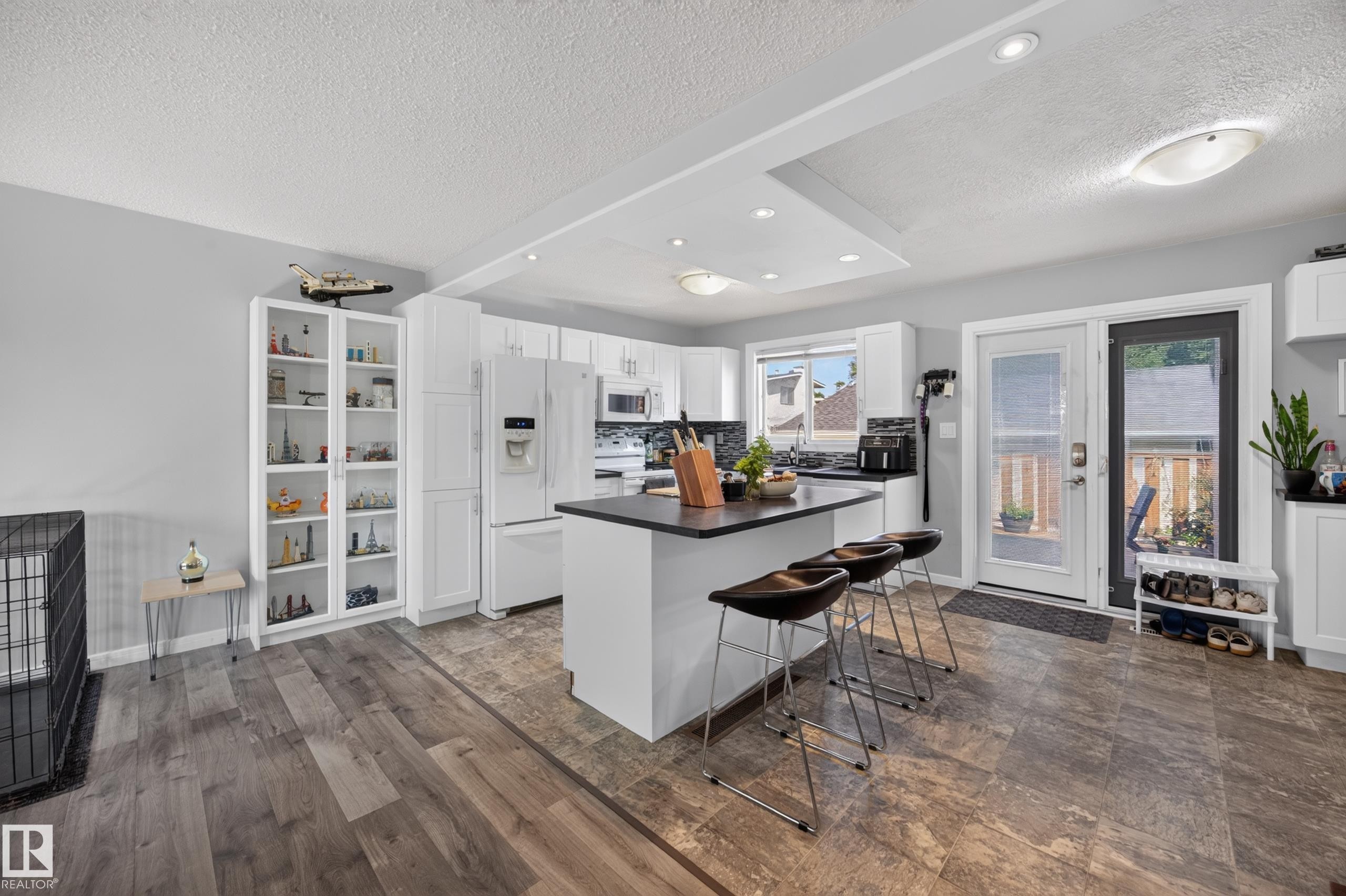 Kitchen featuring a center island with bar seating, white cabinetry, dark countertops, and stainless steel appliances - 156 Clareview Road Nw, Edmonton, AB - Indoor