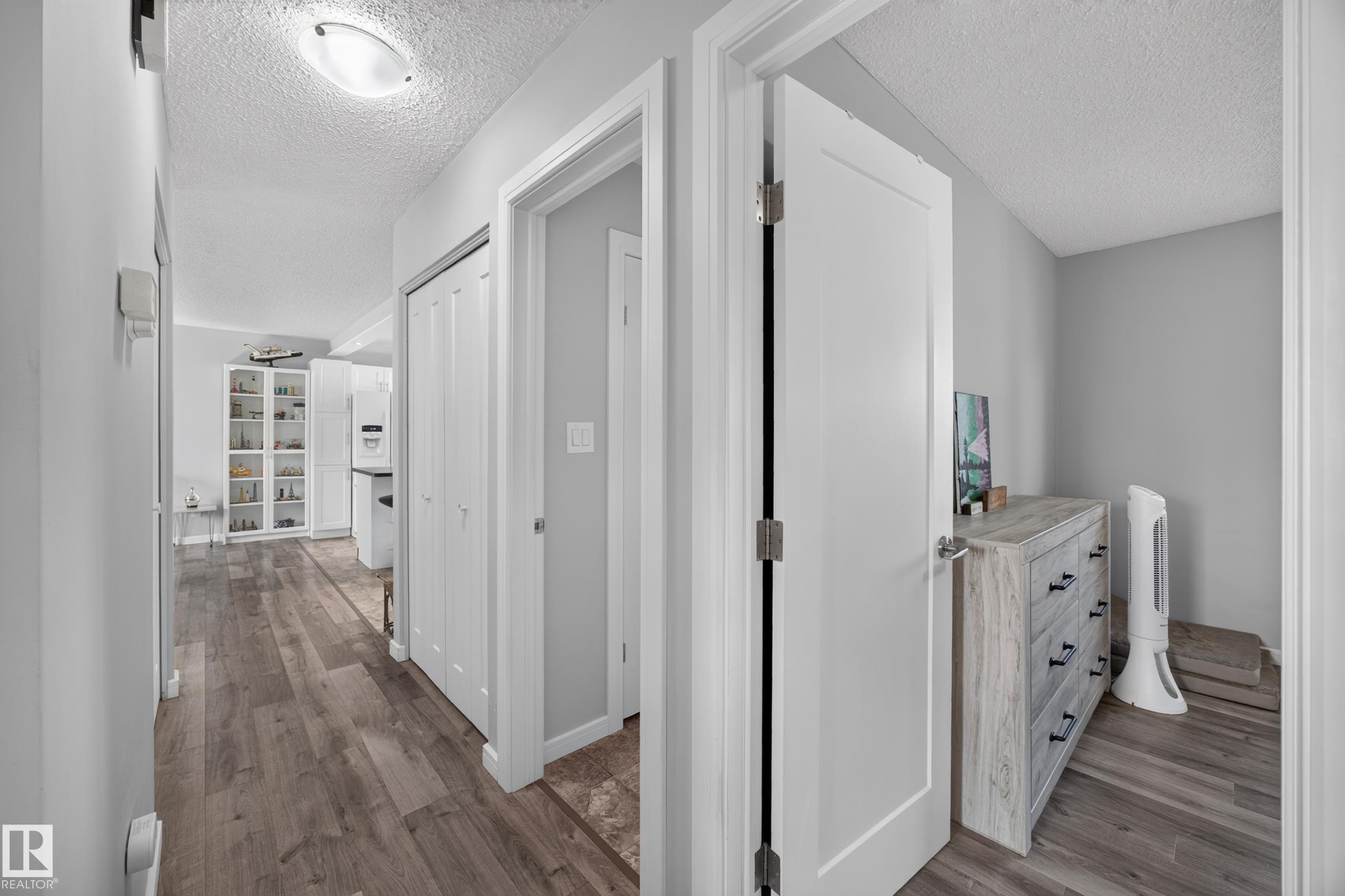 Wood-finish flooring throughout, white interior doors, and a flush-mount ceiling light fixture - 156 Clareview Road Nw, Edmonton, AB - Indoor Photo Showing Other Room