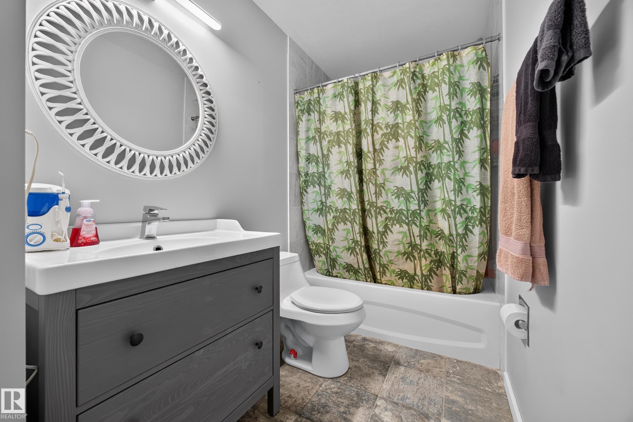 Modern bathroom featuring a charcoal gray vanity with white quartz countertop and integrated sink, chrome wall-mounted faucet, and circular illuminated mirror - 156 Clareview Road Nw, Edmonton, AB - Indoor Photo Showing Bathroom
