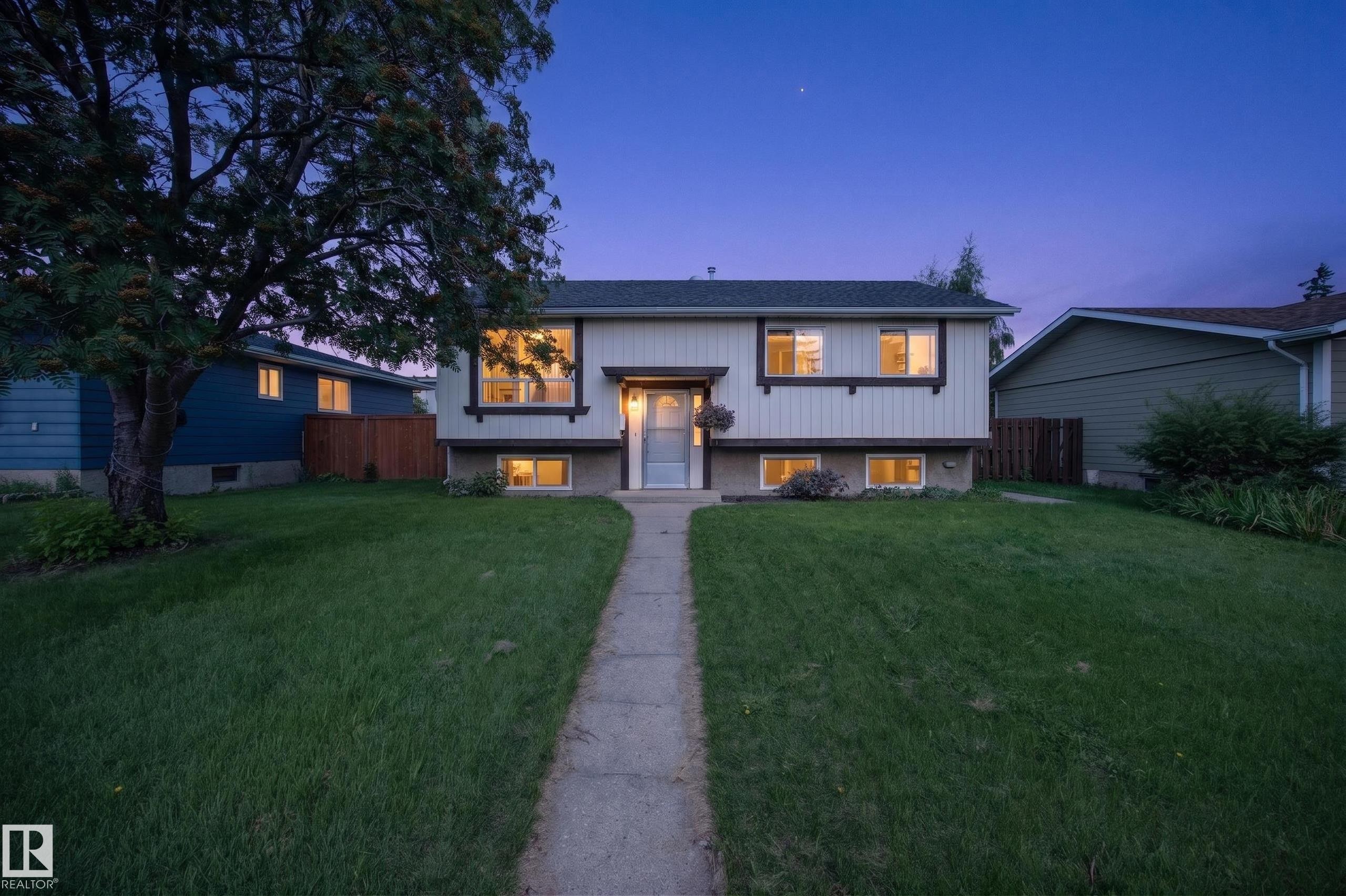 Split-level residence featuring a prominent front lawn, concrete pathway, and multiple windows across two levels - 156 Clareview Road Nw, Edmonton, AB - Outdoor