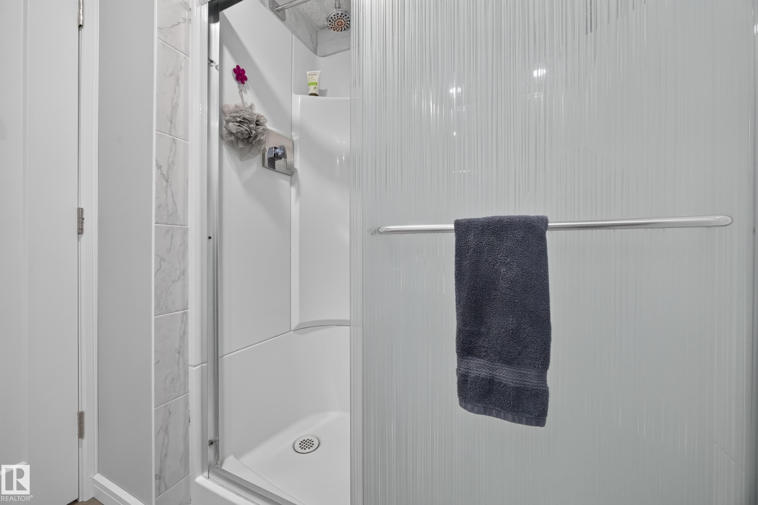 Shower enclosure featuring a built-in shelf, marble-look tile, and a textured privacy glass panel - 156 Clareview Road Nw, Edmonton, AB - Indoor Photo Showing Bathroom