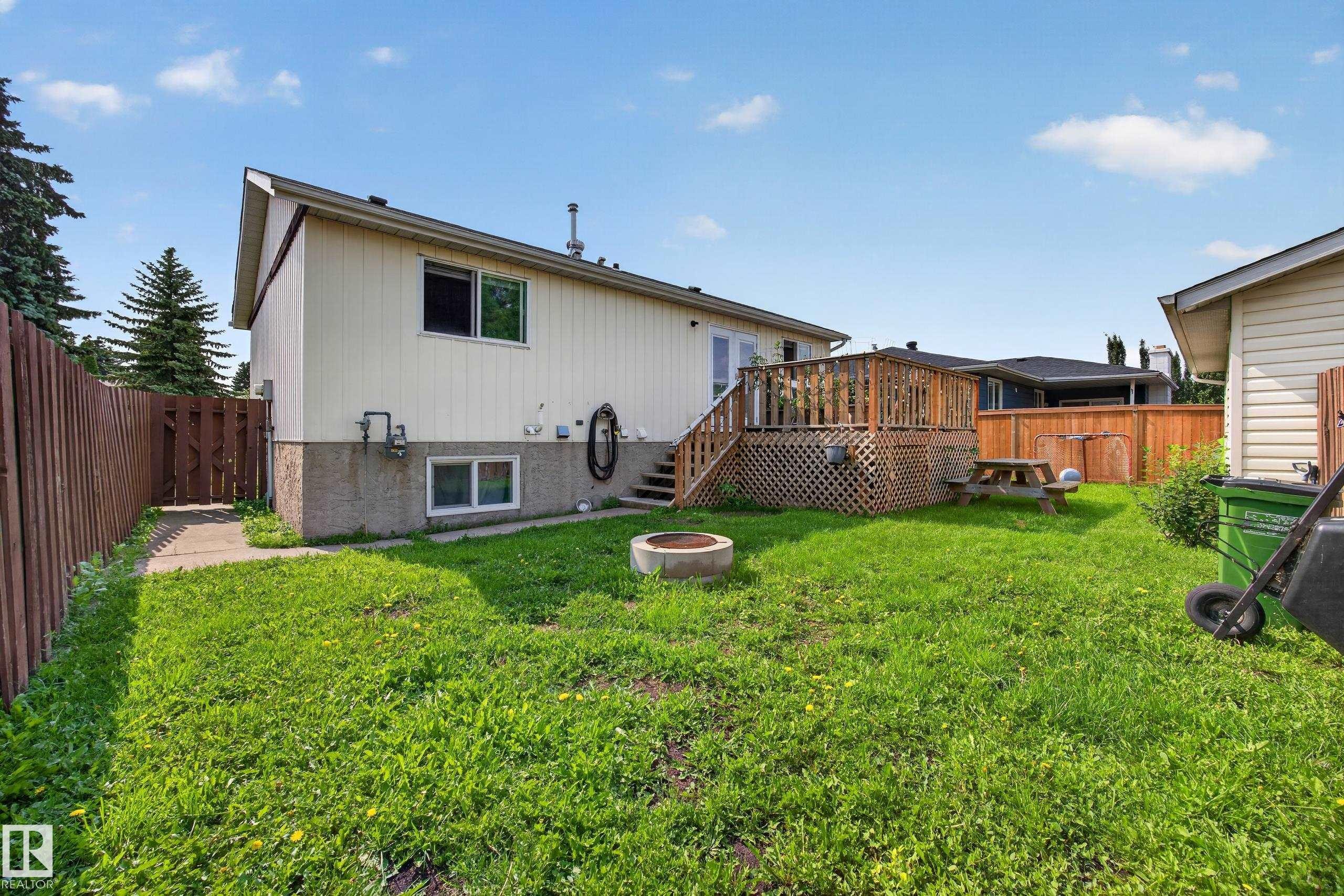 Expansive backyard with a wooden fence, concrete patio, and elevated wood deck - 156 Clareview Road Nw, Edmonton, AB - Outdoor With Exterior