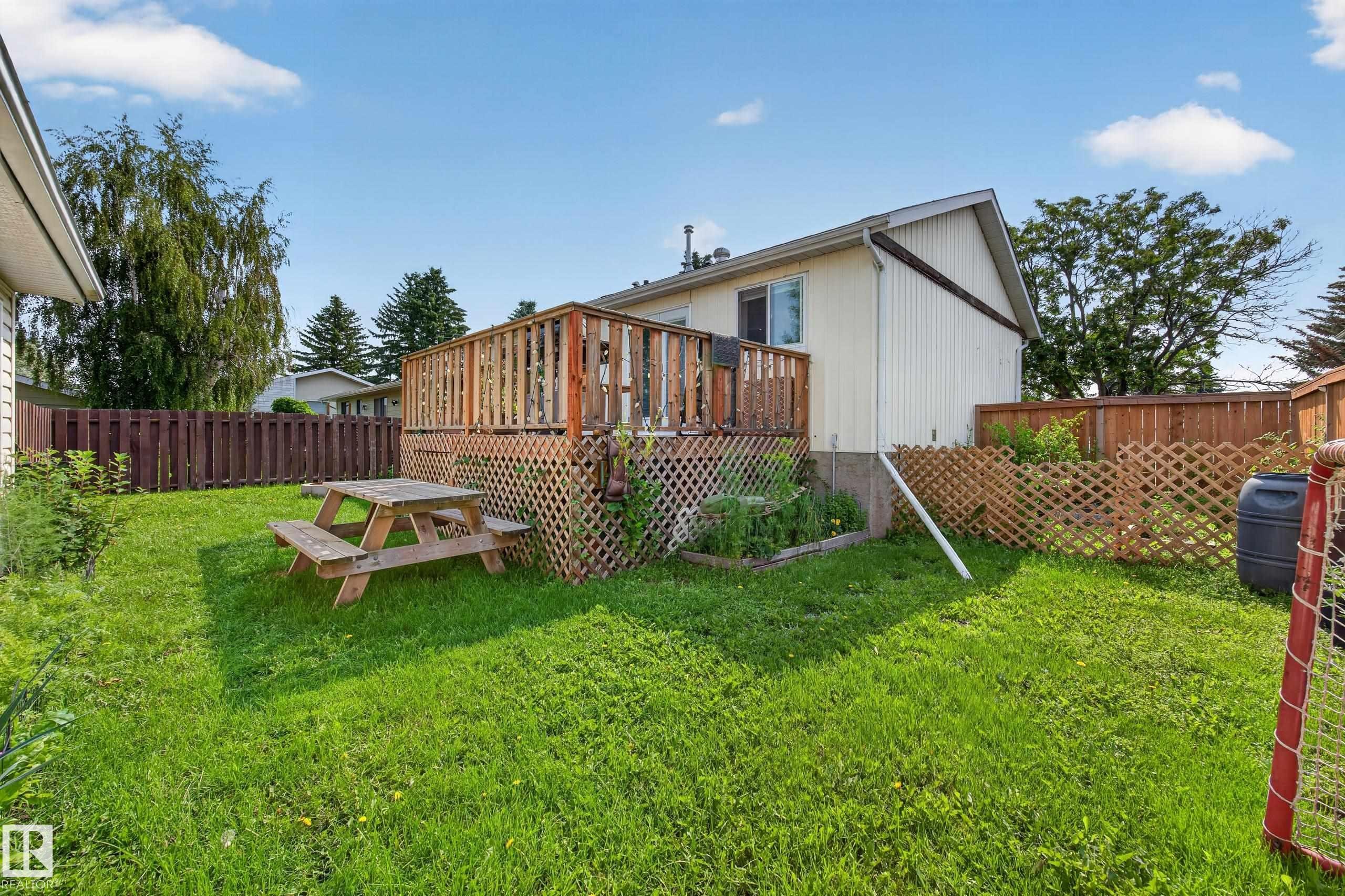 Expansive green space featuring a wooden deck with lattice skirting and privacy fencing - 156 Clareview Road Nw, Edmonton, AB - Outdoor
