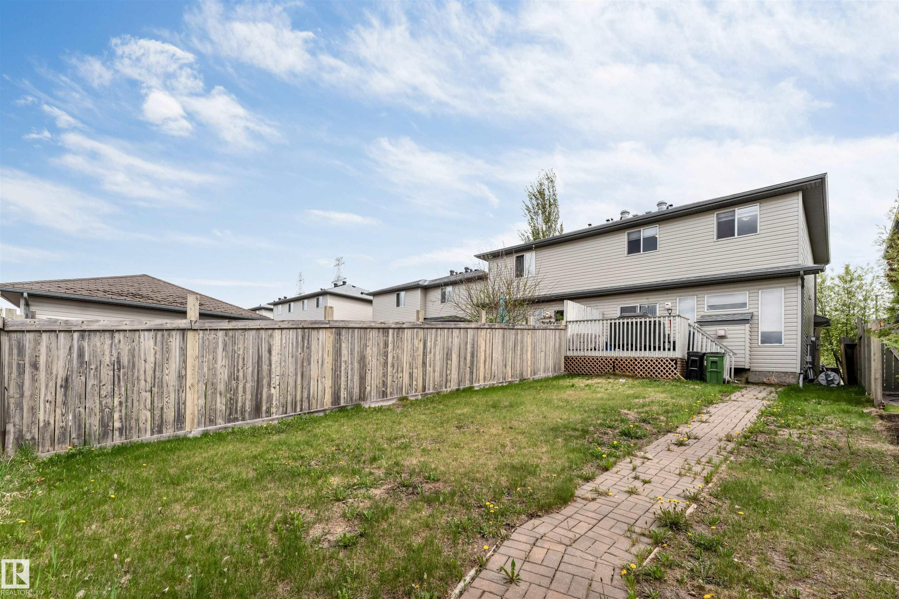 Rear exterior featuring a wood deck, brick pathway, and fenced yard - 3032 31 Avenue Nw, Edmonton, AB - Outdoor