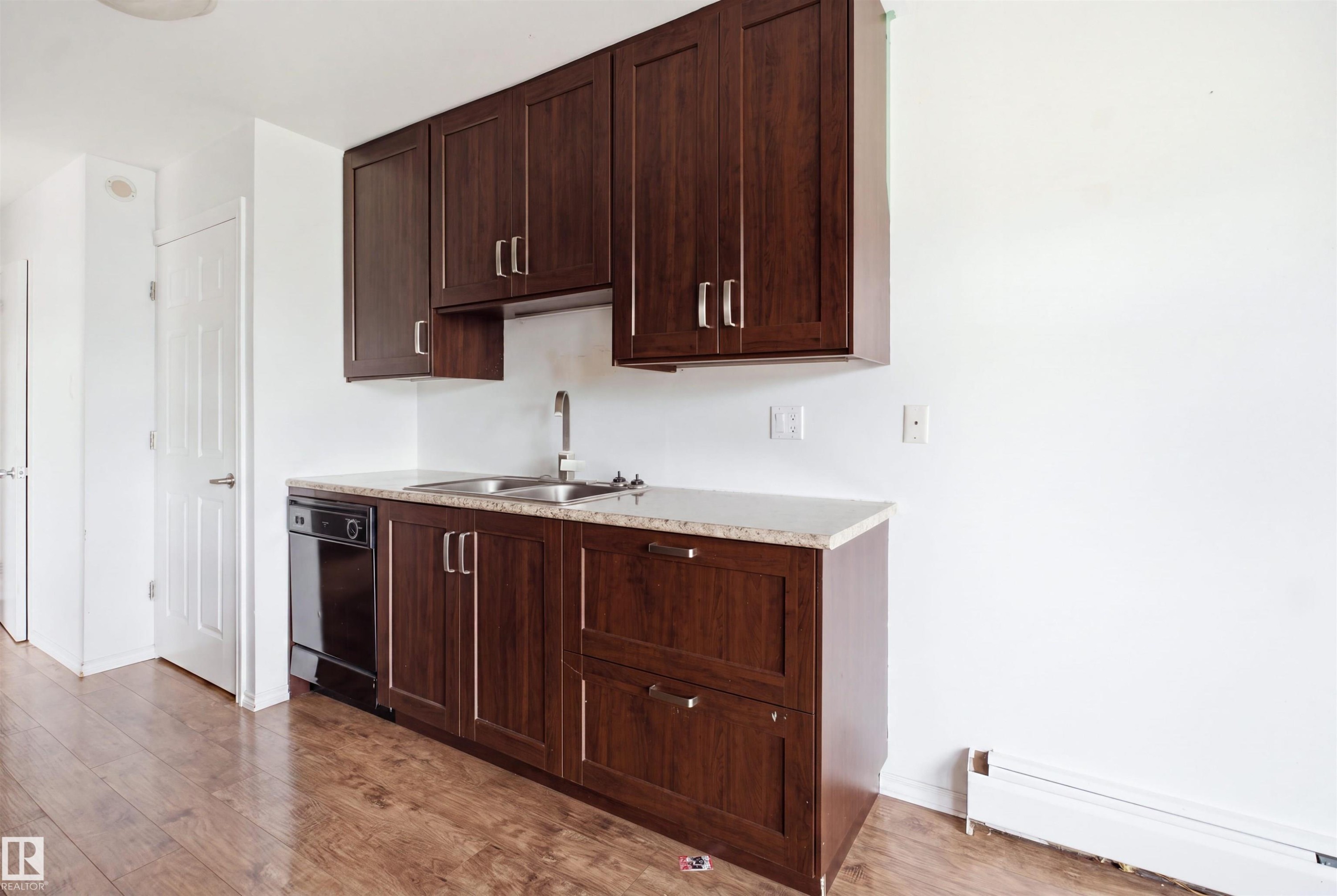 Dark wood-finish cabinetry with silver-tone hardware, a dual stainless steel sink, and a black dishwasher - 7825 159 Street Nw, Edmonton, AB - Indoor Photo Showing Kitchen With Double Sink