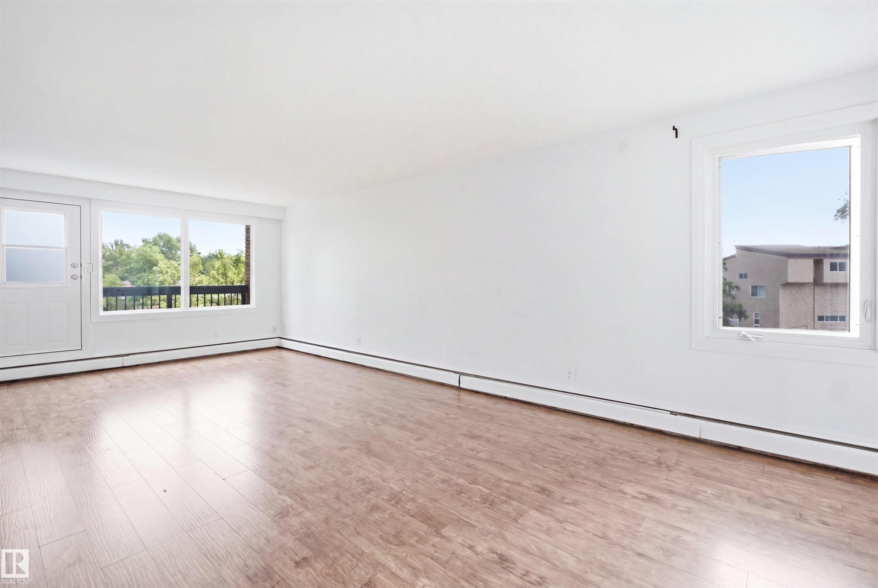 Wood-finish flooring, white walls, white trim, and multiple windows - 7825 159 Street Nw, Edmonton, AB - Indoor Photo Showing Other Room
