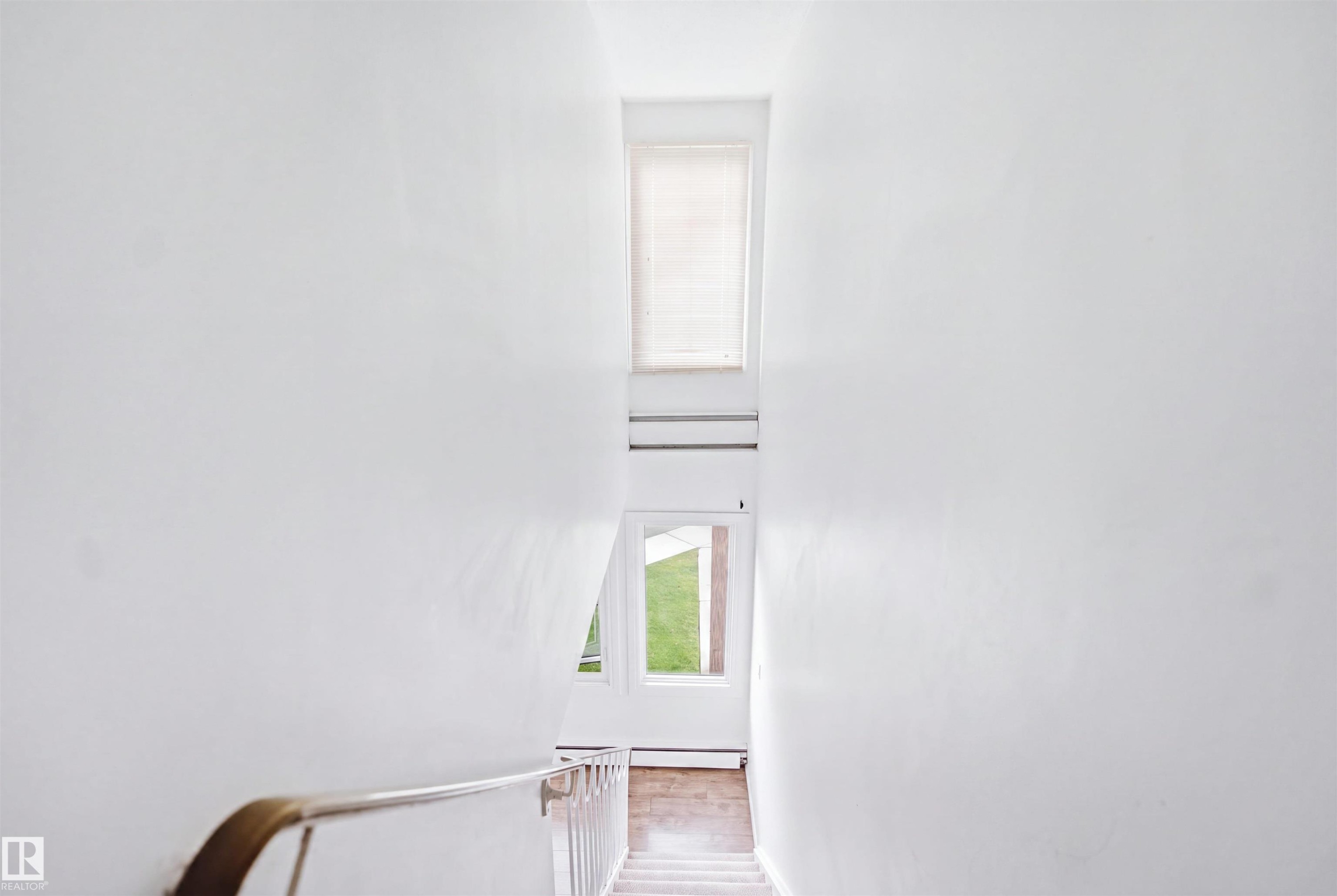 Upper-level window, lower-level windows, interior wall with a handrail, and carpeted stairs - 7825 159 Street Nw, Edmonton, AB - Photo Showing Other Room