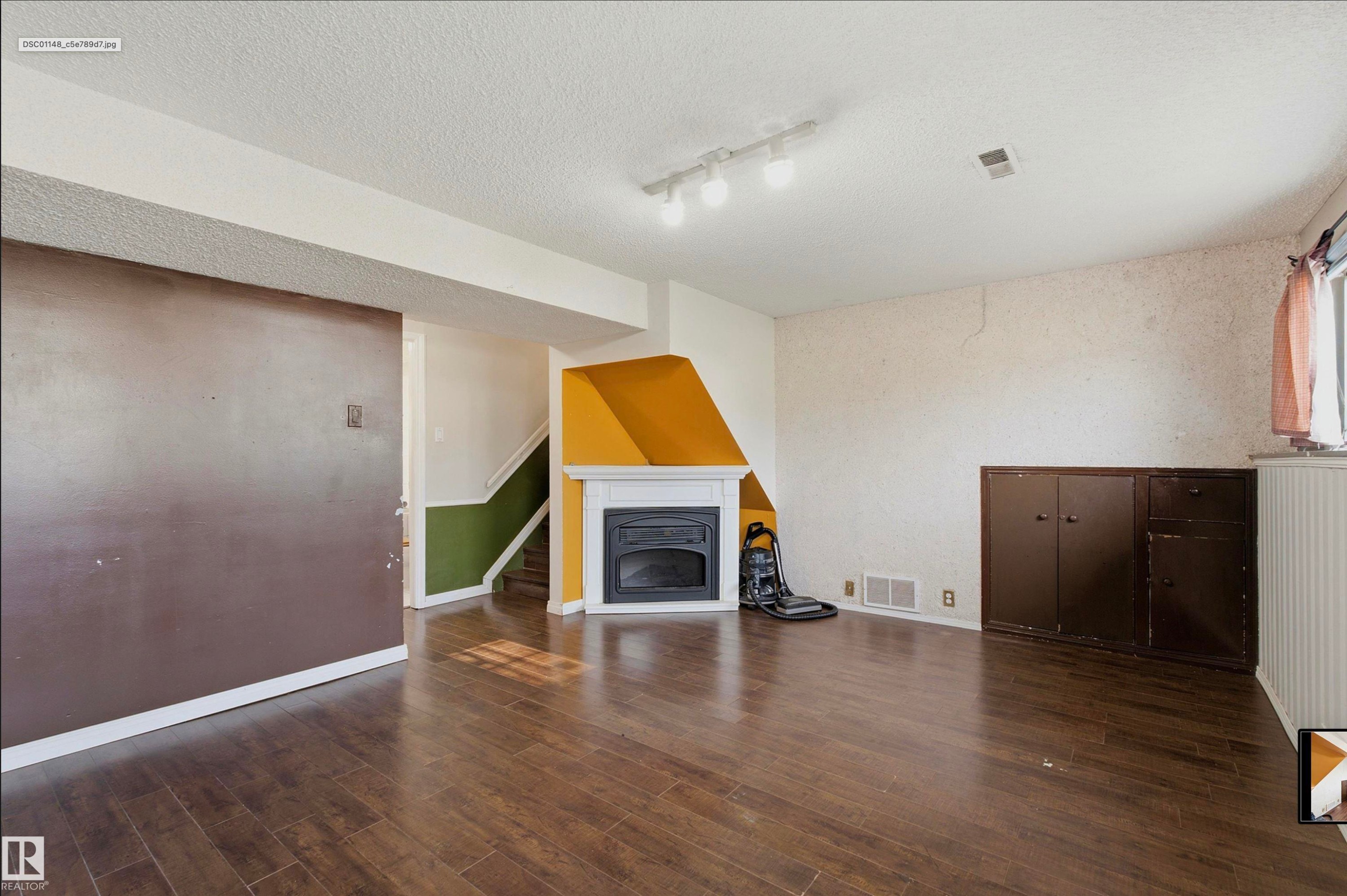 Wood-finish flooring throughout, white fireplace mantel, and built-in cabinetry - 13604 90A Street Nw, Edmonton, AB - Indoor With Fireplace