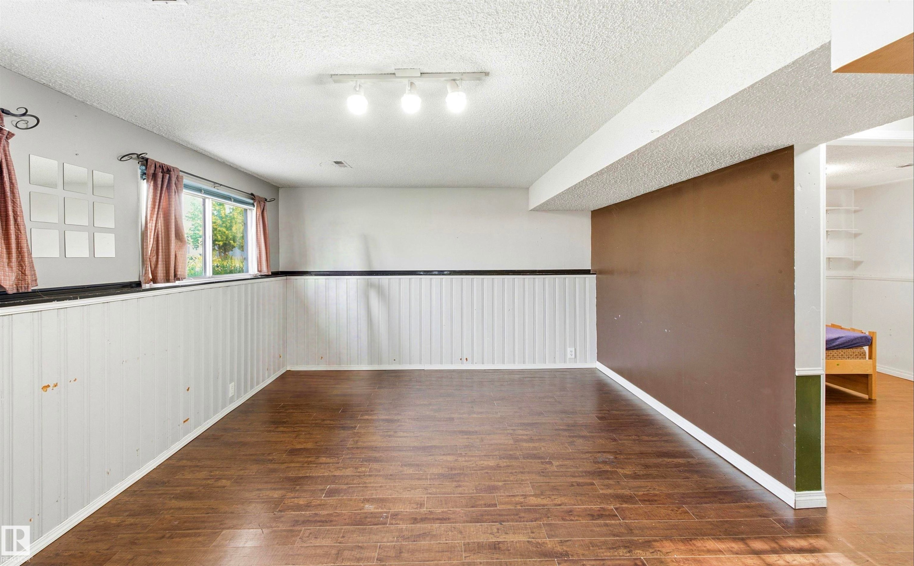Wood-finish flooring, white paneled wainscoting, and track lighting - 13604 90A Street Nw, Edmonton, AB - Indoor Photo Showing Other Room