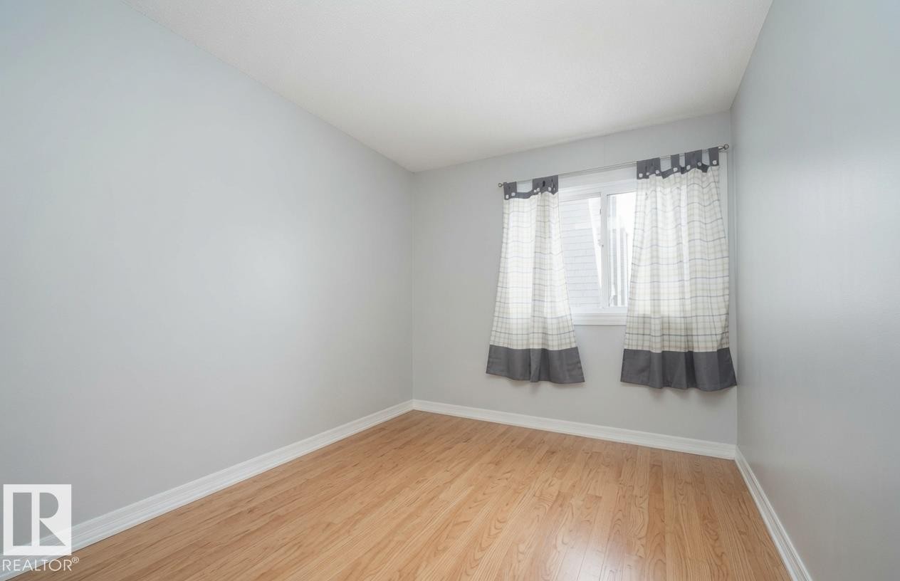 Light wood-finish flooring, light gray wall paint, and a white framed window - #31 11255 31 Av Nw, Edmonton, AB - Indoor Photo Showing Other Room