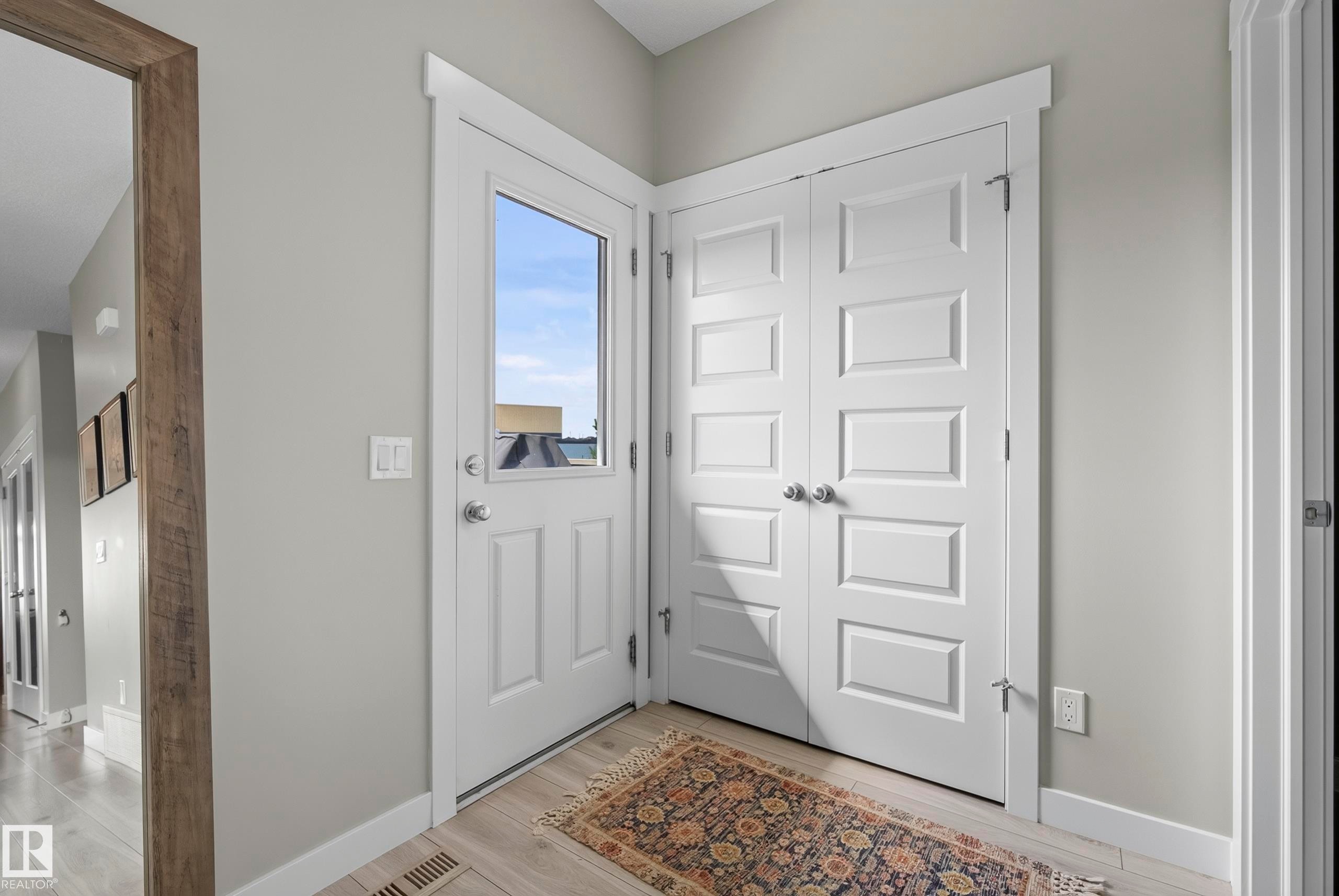 White paneled entry door with glass insert, light wood-finish flooring, and white bifold closet doors - 45 Joyal Way, St. Albert, AB - Indoor Photo Showing Other Room