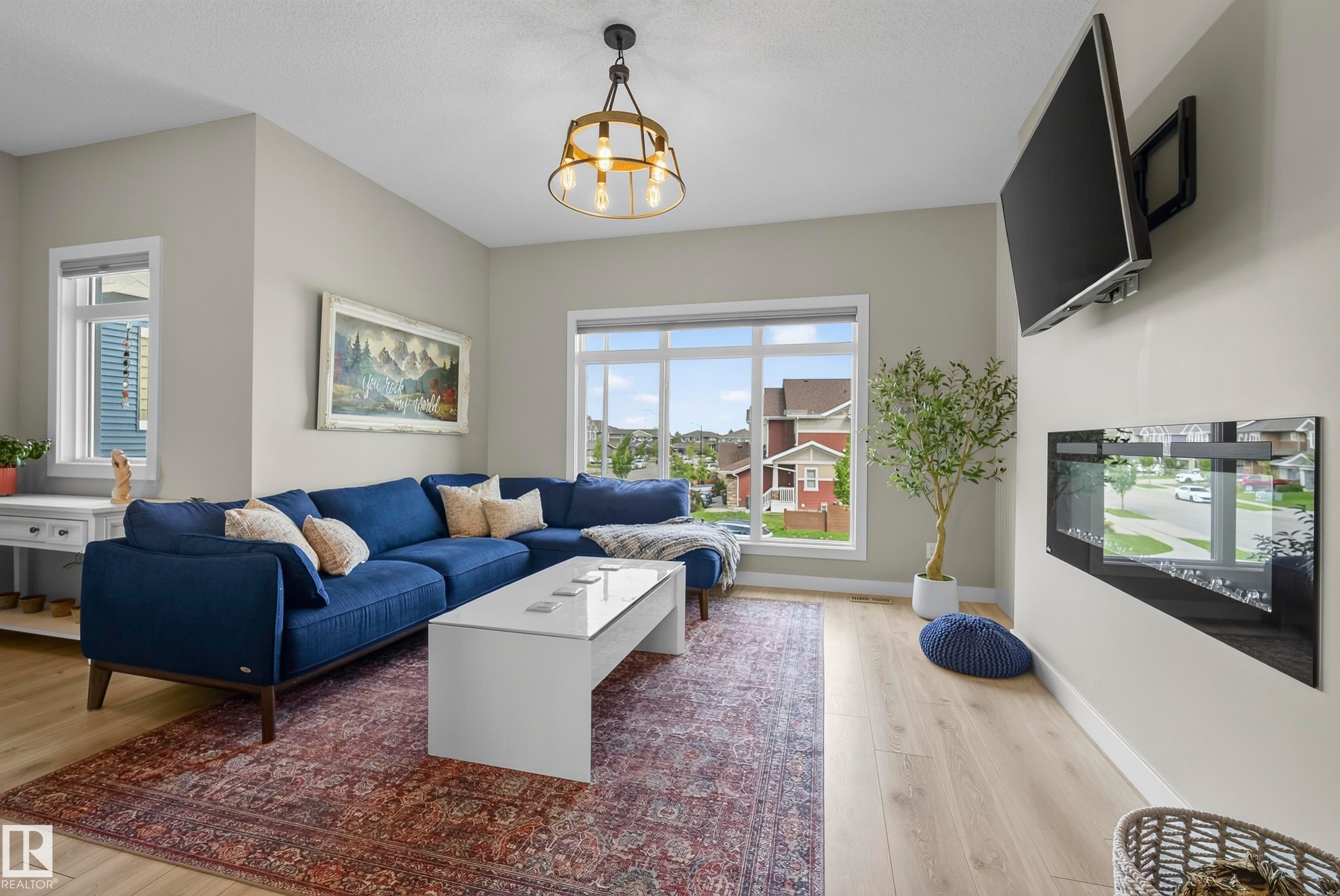 Light-toned wood-finish flooring, recessed lighting, and a modern fireplace with a wall-mounted television - 45 Joyal Way, St. Albert, AB - Indoor Photo Showing Living Room