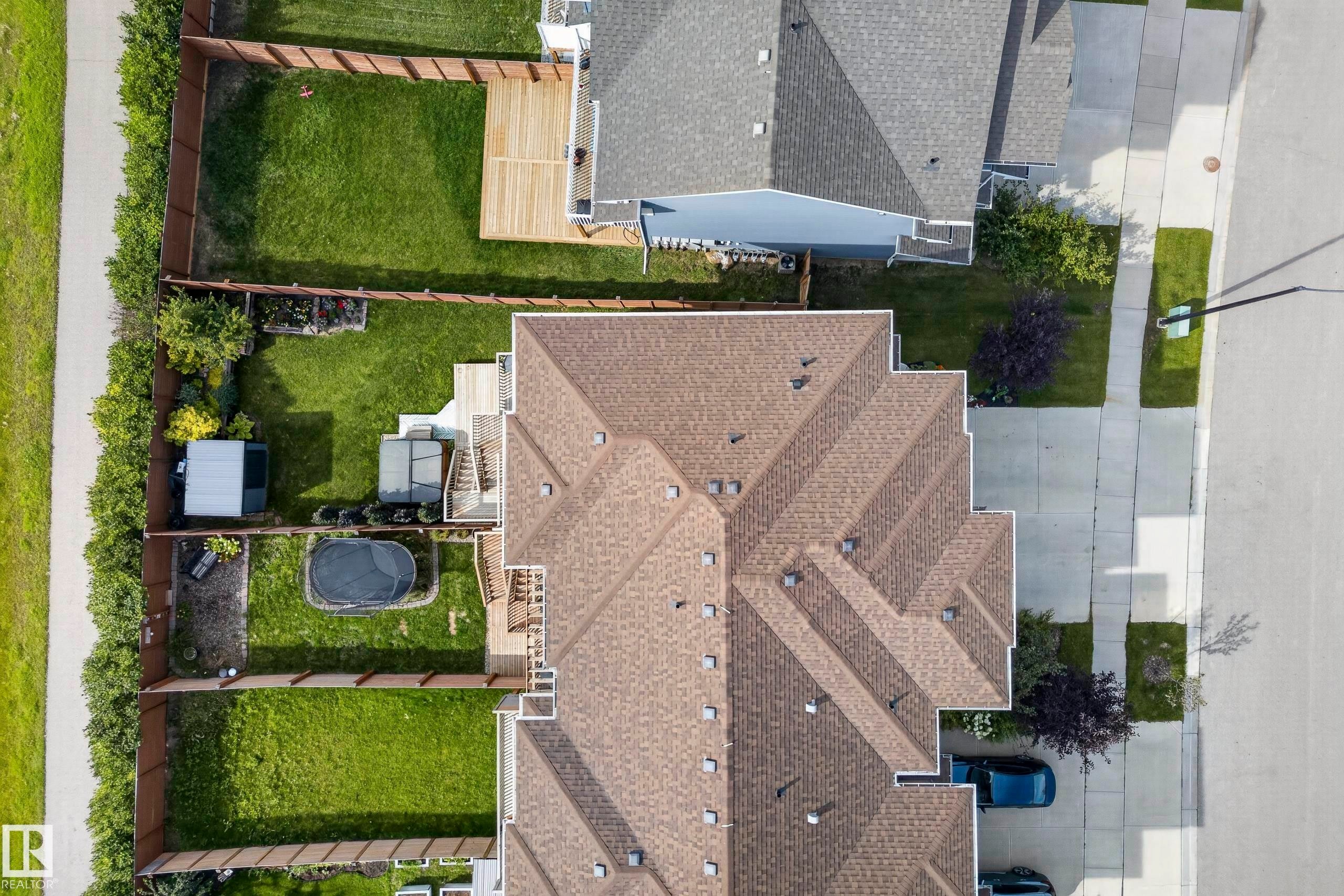Asphalt shingle roof, paved driveway, concrete sidewalk, fenced backyard, and a wooden deck - 45 Joyal Way, St. Albert, AB - Outdoor