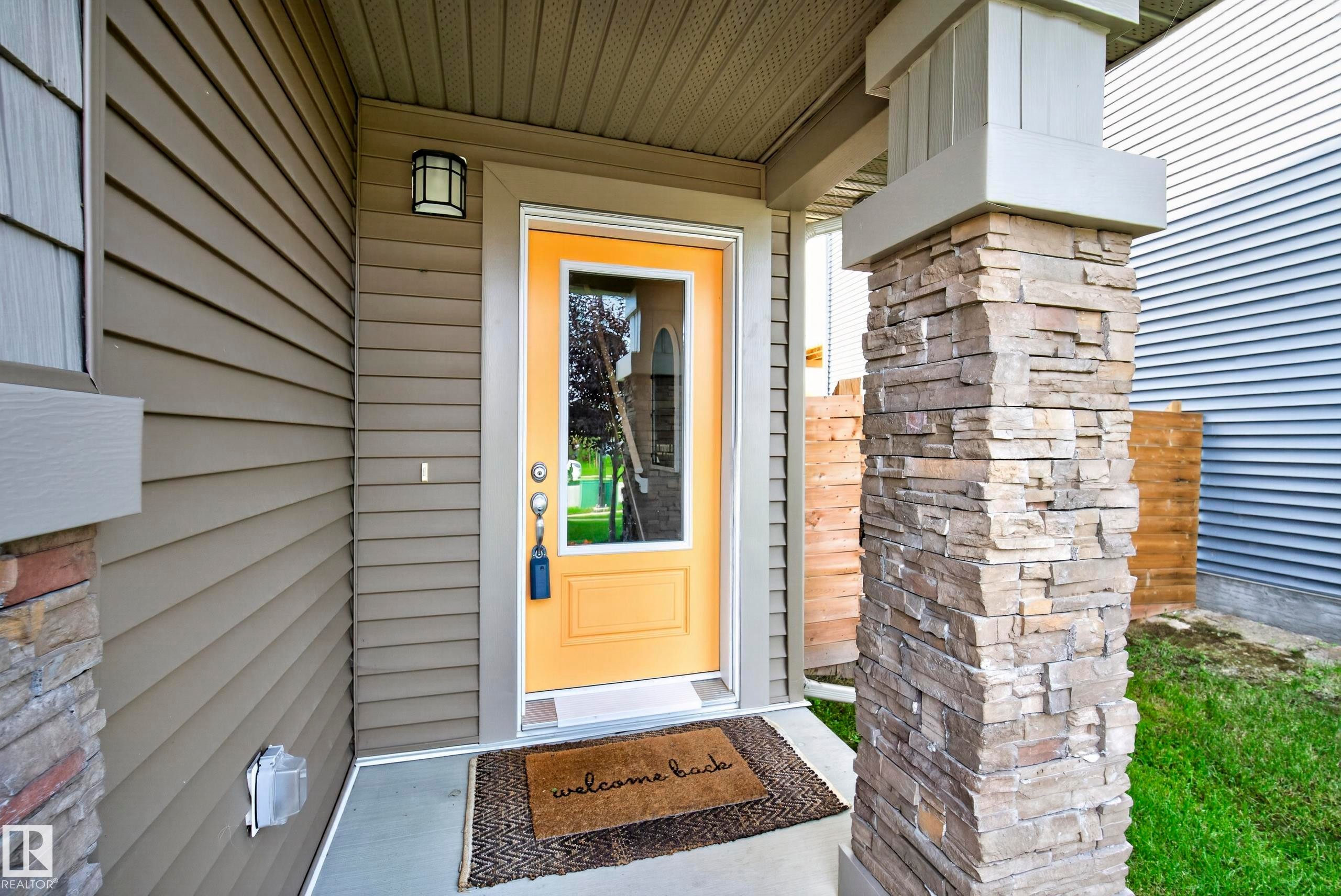 Stone-clad column, horizontal siding, and a vibrant yellow full-light door - 45 Joyal Way, St. Albert, AB - Outdoor With Exterior