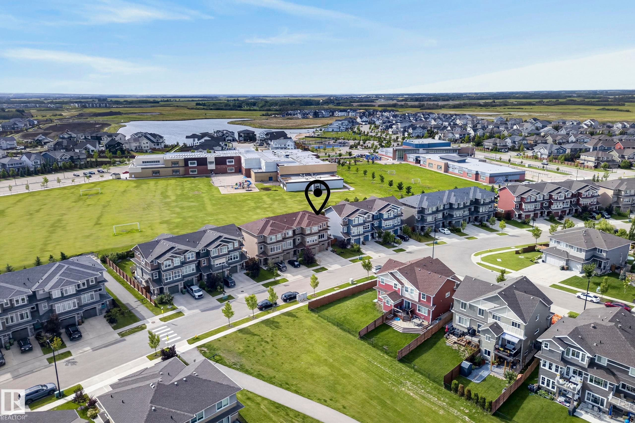 Aerial perspective featuring a residential street, a large green field, a body of water, and surrounding neighborhood homes - 45 Joyal Way, St. Albert, AB - Outdoor With View