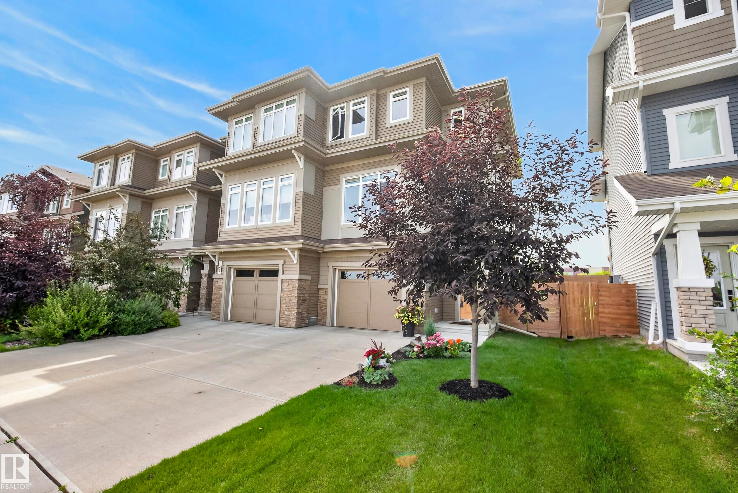 Three-story structure featuring a combination of siding and stone veneer, multiple windows, and a two-car garage with individual doors - 45 Joyal Way, St. Albert, AB - Outdoor With Facade