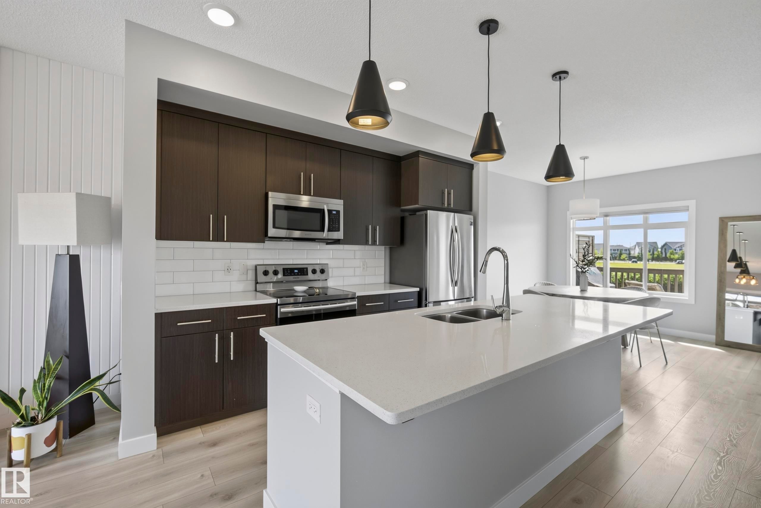 Open-concept kitchen featuring dark wood-finish cabinetry, stainless steel appliances, and a white subway tile backsplash - 45 Joyal Way, St. Albert, AB - Indoor Photo Showing Kitchen With Double Sink With Upgraded Kitchen