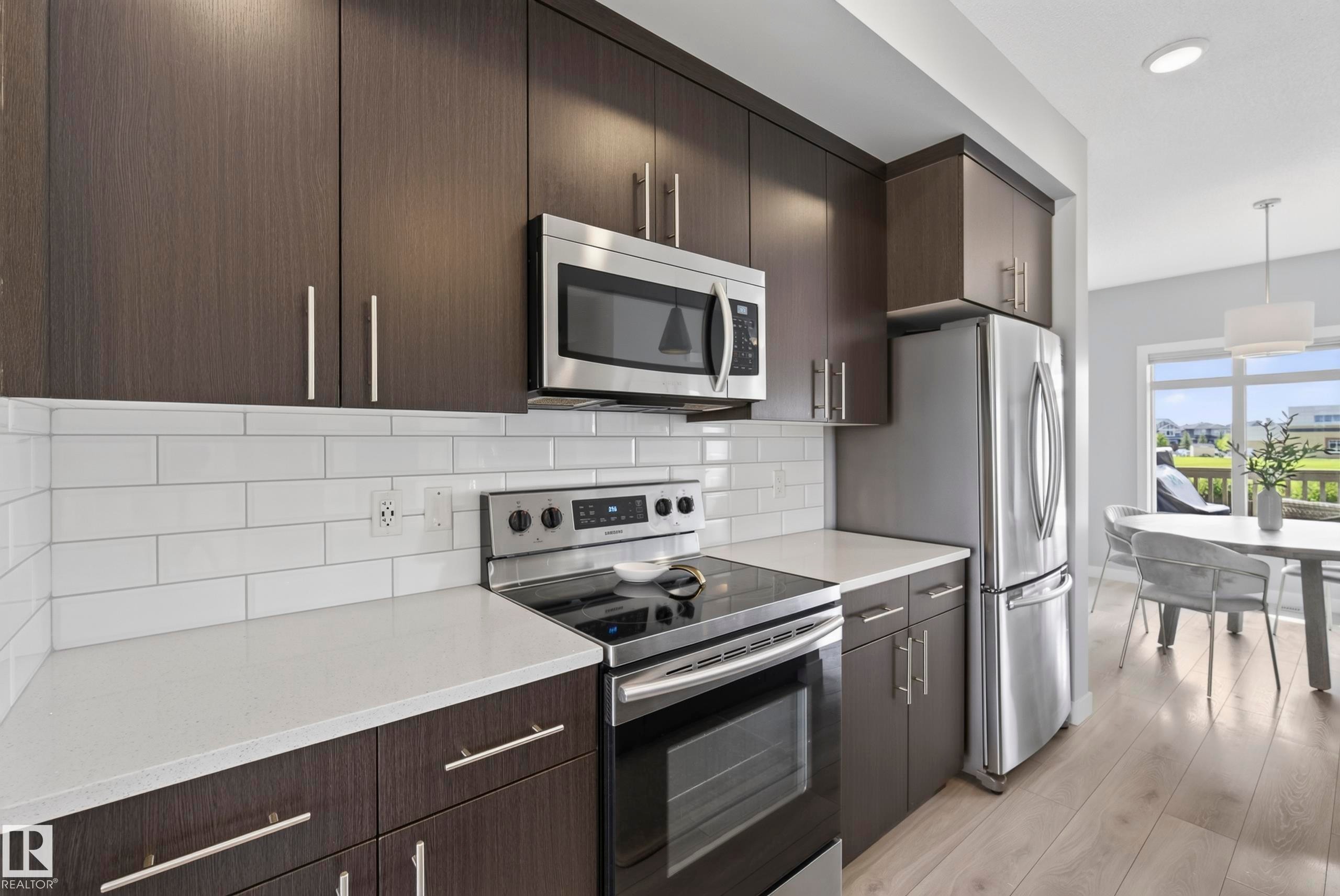 Kitchen featuring dark wood-finish cabinetry, stainless steel appliances, a white subway tile backsplash, and white countertops - 45 Joyal Way, St. Albert, AB - Indoor Photo Showing Kitchen With Upgraded Kitchen