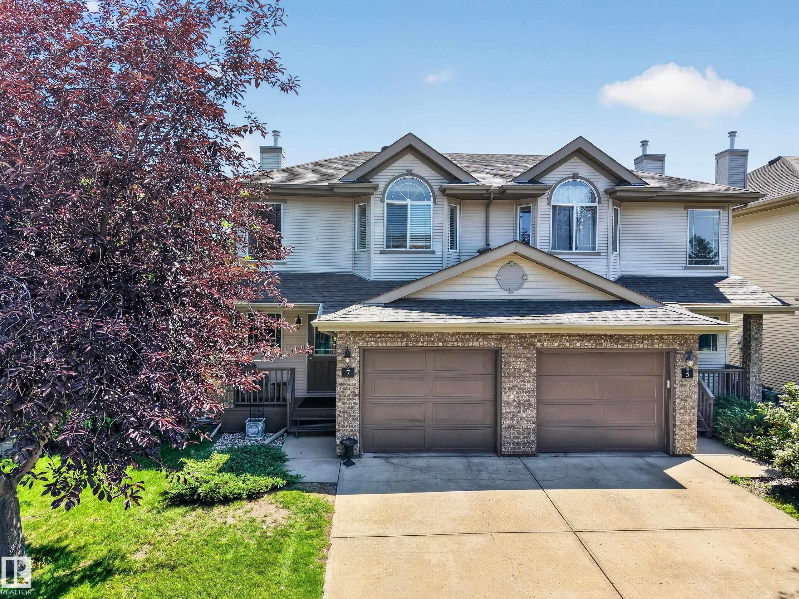 Two-story residence featuring light-toned siding and a prominent two-car garage with brick detailing - #7 155 Crocus Cr, Sherwood Park, AB - Outdoor With Facade