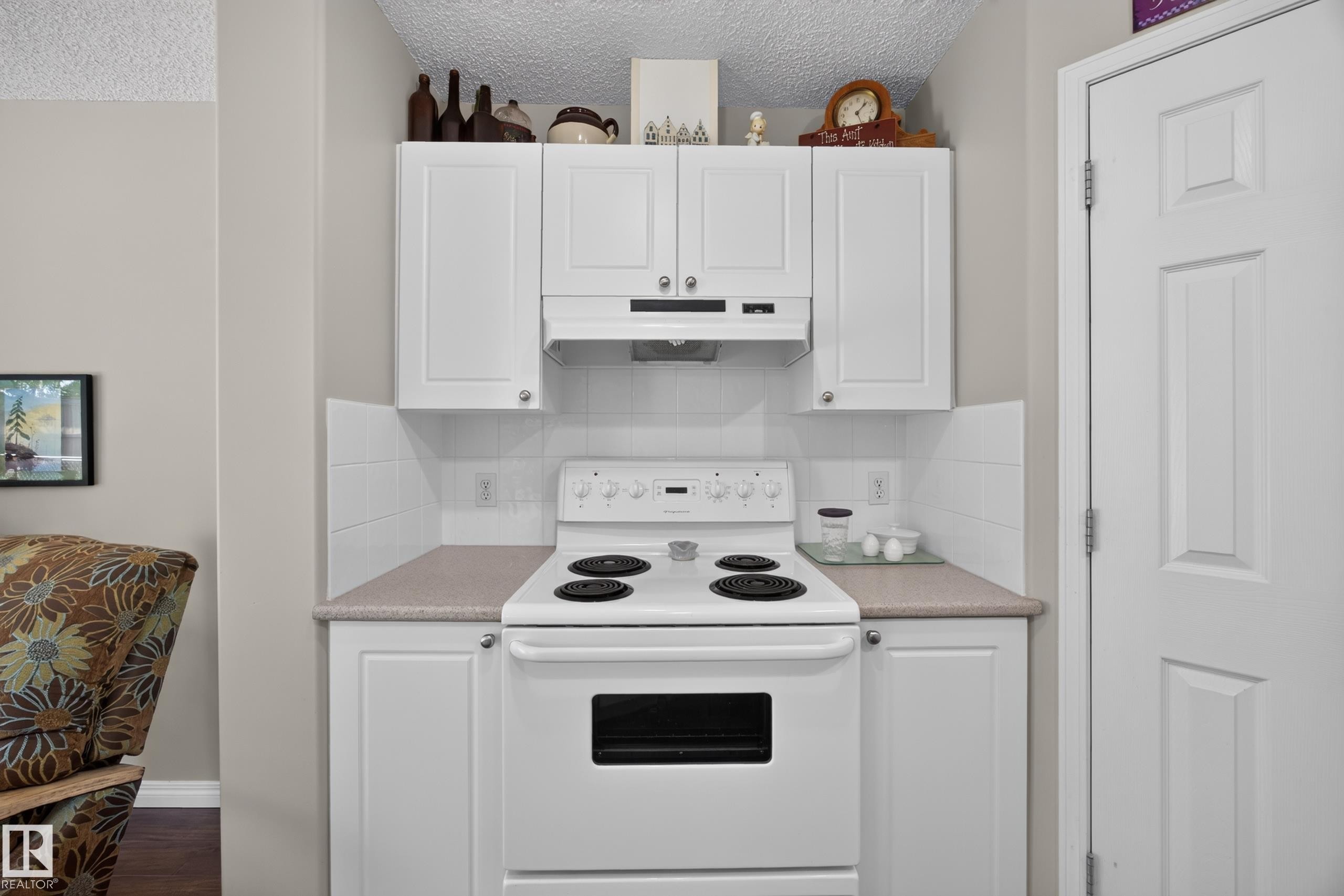 Kitchen area featuring white cabinetry with brushed nickel hardware, a white electric range, and a white tile backsplash - #7 155 Crocus Cr, Sherwood Park, AB - Indoor Photo Showing Kitchen