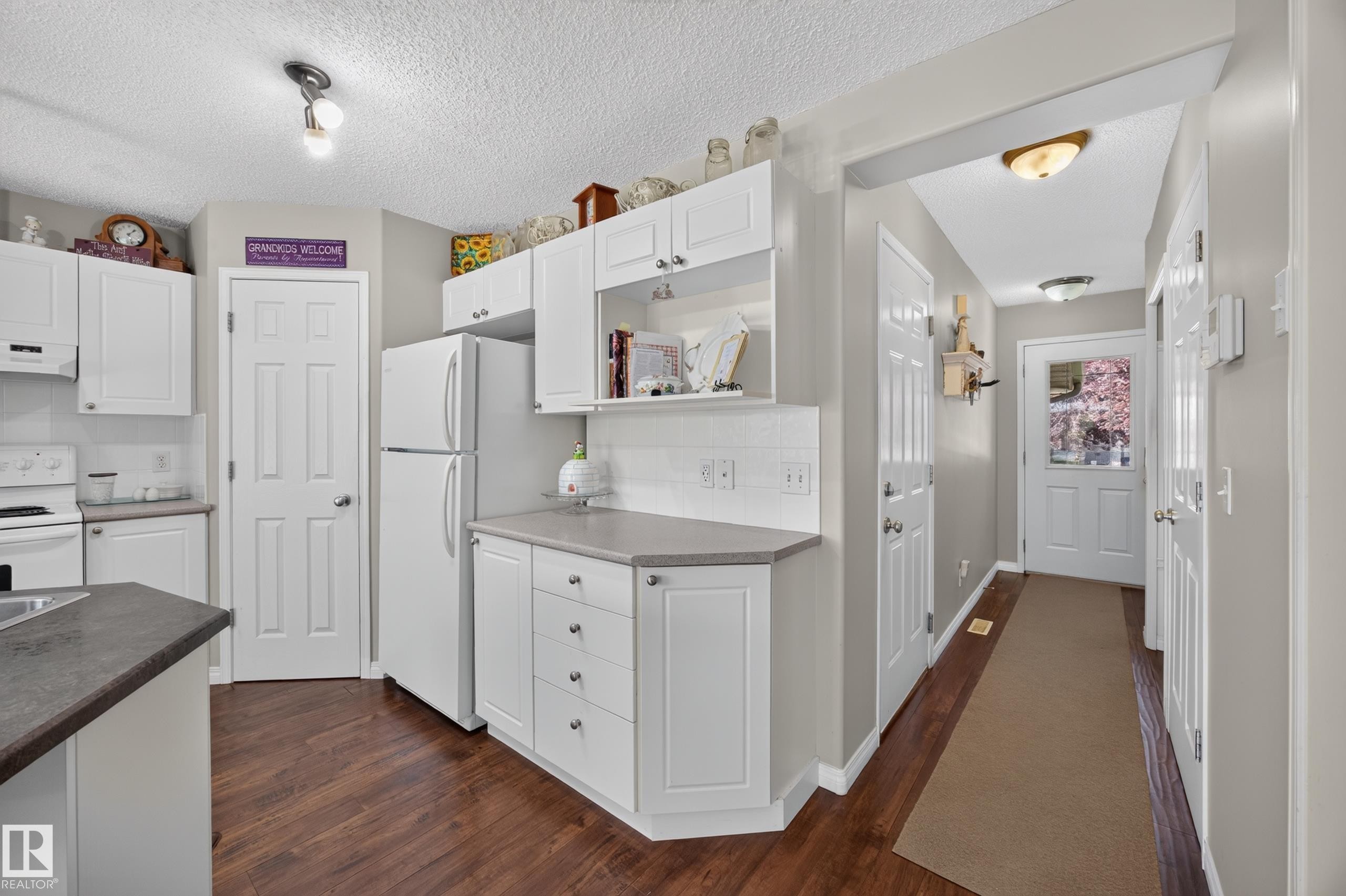 Kitchen featuring white cabinetry, a white tile backsplash, and dark wood-finish flooring - #7 155 Crocus Cr, Sherwood Park, AB - Indoor Photo Showing Kitchen