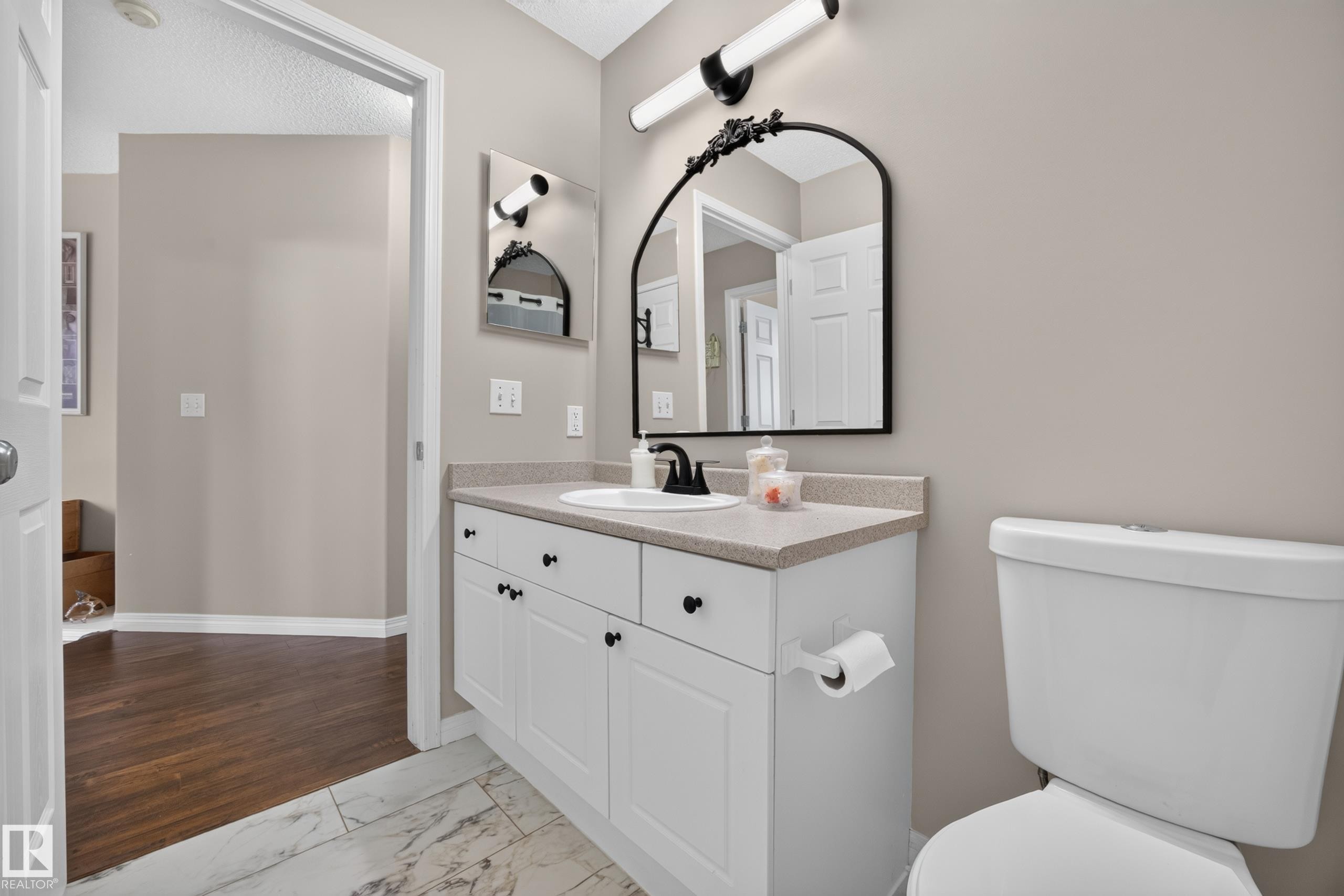 Bathroom featuring a white vanity with cabinet storage, a light-toned countertop, and a black-framed mirror - #7 155 Crocus Cr, Sherwood Park, AB - Indoor Photo Showing Bathroom