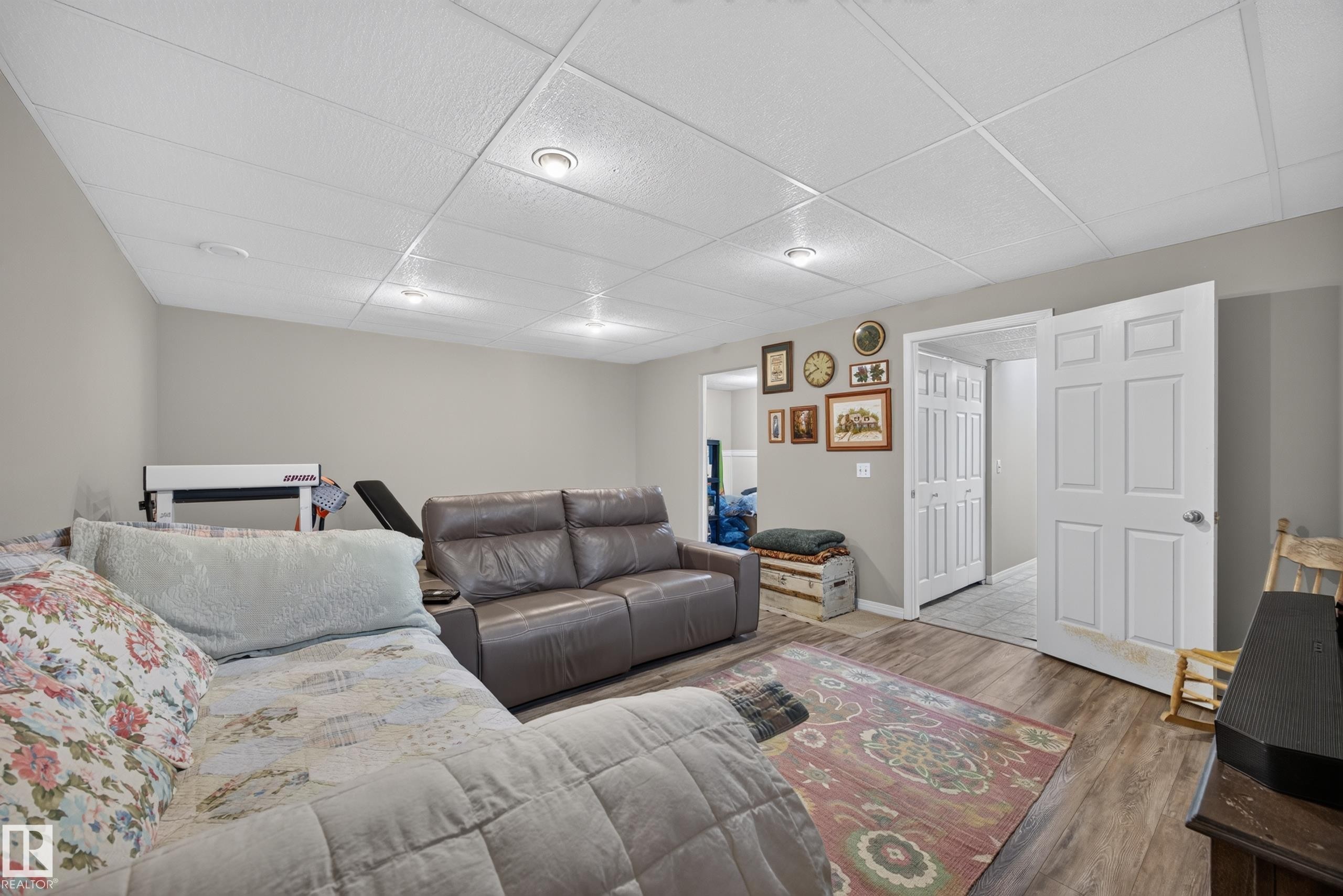 Open-concept living area with wood-finish flooring, drop ceiling with recessed lighting, and neutral wall tones - #7 155 Crocus Cr, Sherwood Park, AB - Indoor Photo Showing Other Room