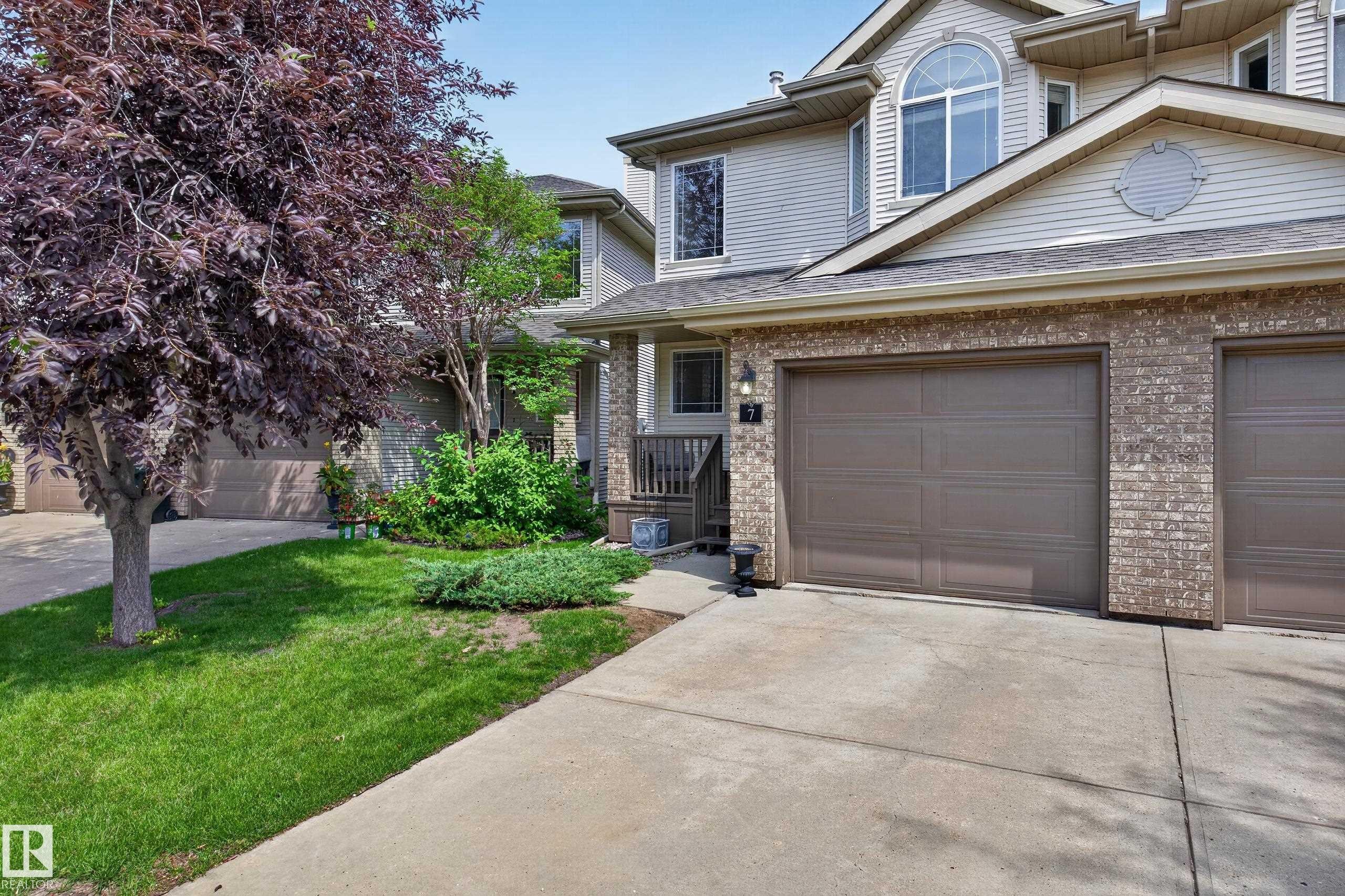Two-story siding and brick facade featuring a double garage, arched window, and covered entryway - #7 155 Crocus Cr, Sherwood Park, AB - Outdoor