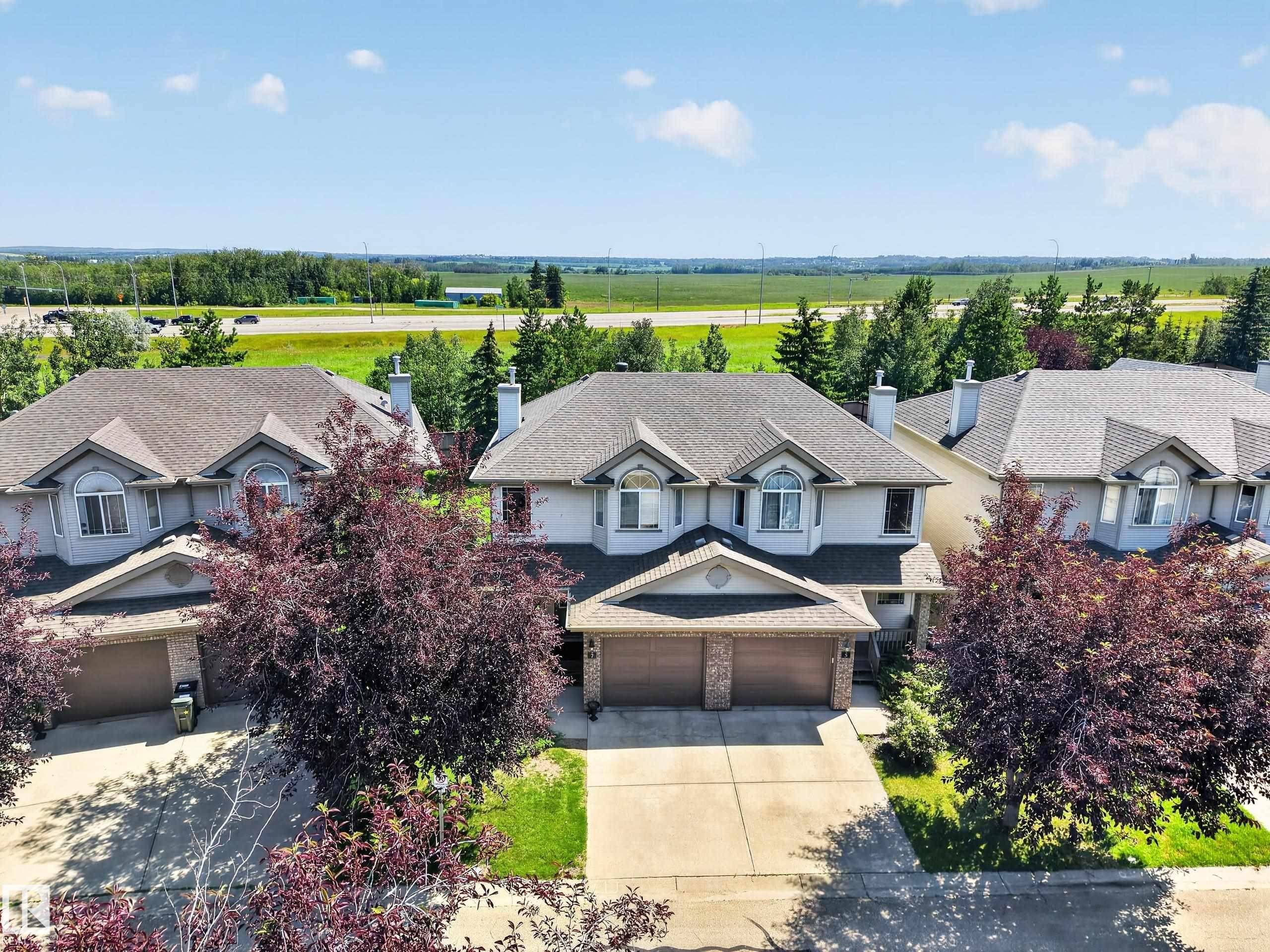 Two-story residence featuring a two-car garage, dormer windows, a gabled entry, mature landscaping, and a paved driveway - #7 155 Crocus Cr, Sherwood Park, AB - Outdoor With Facade