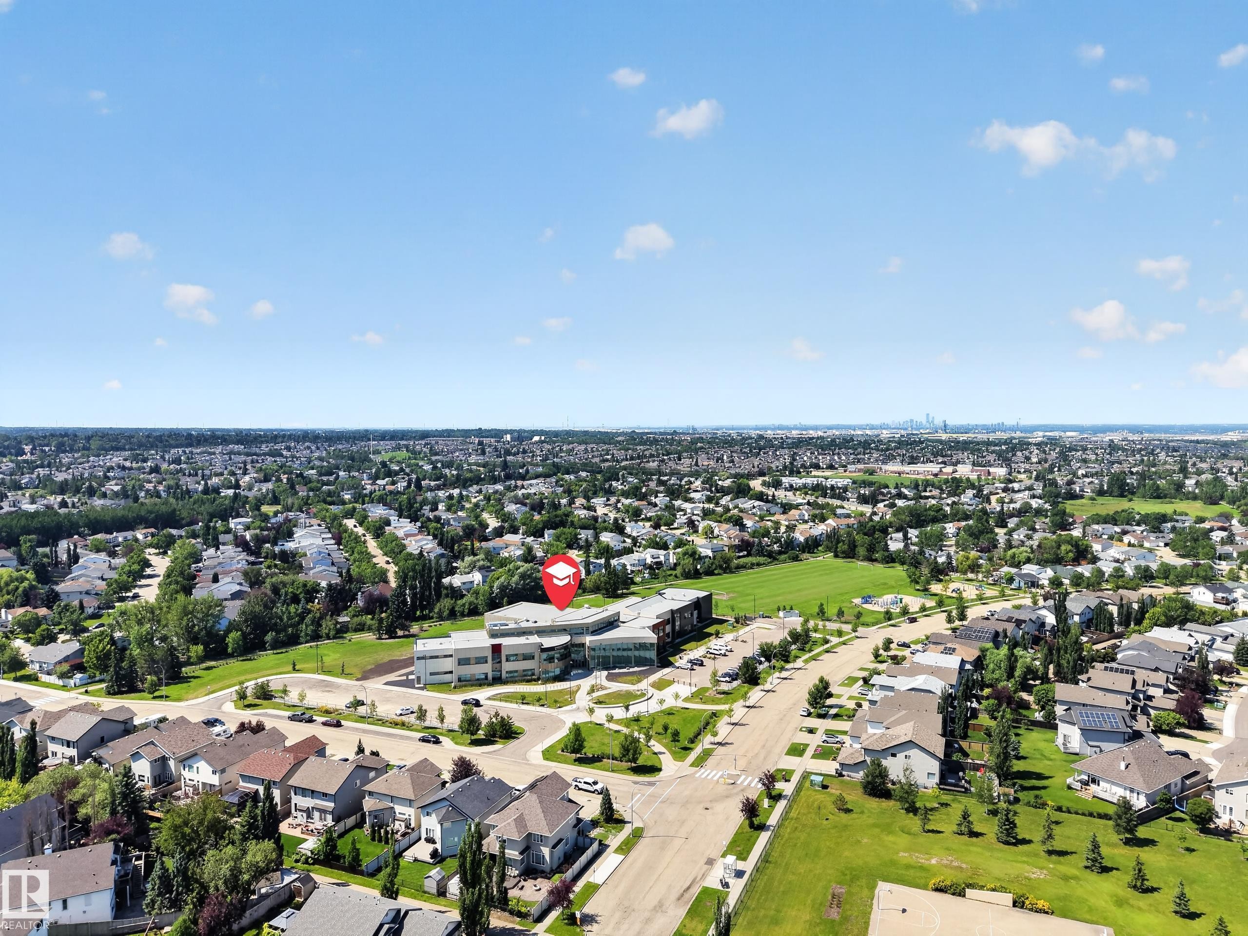Expansive residential area featuring numerous single-family homes, abundant green spaces, and a prominent institutional building with modern architecture - #7 155 Crocus Cr, Sherwood Park, AB - Outdoor With View